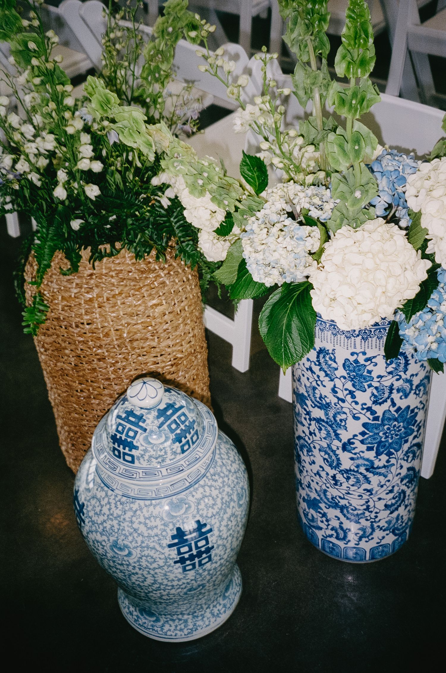 Blue and white chinoiserie vases filled with white hydrangeas and greenery as wedding decor.