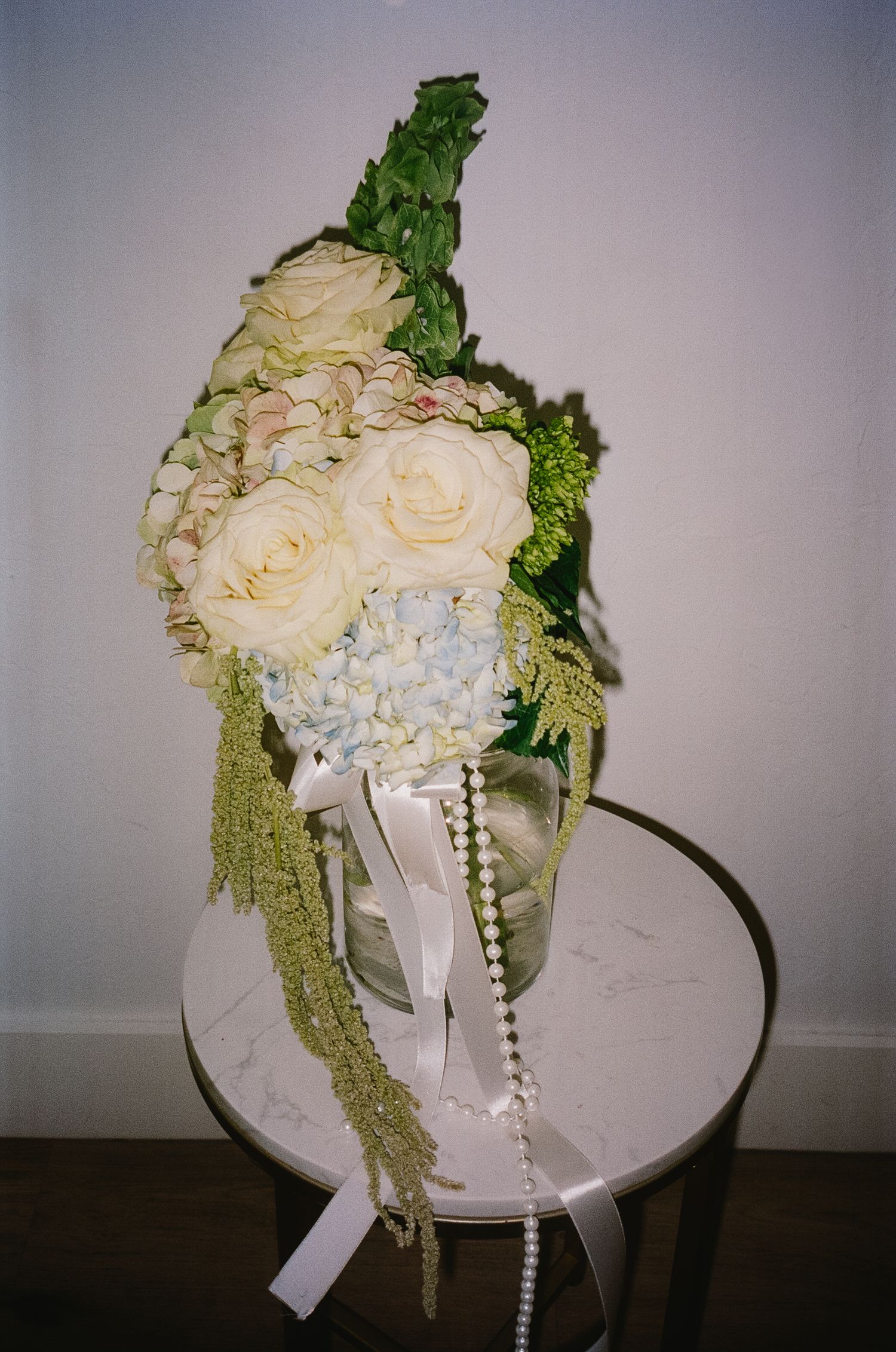 White roses and pearl strands arranged in an elegant bridal bouquet display.