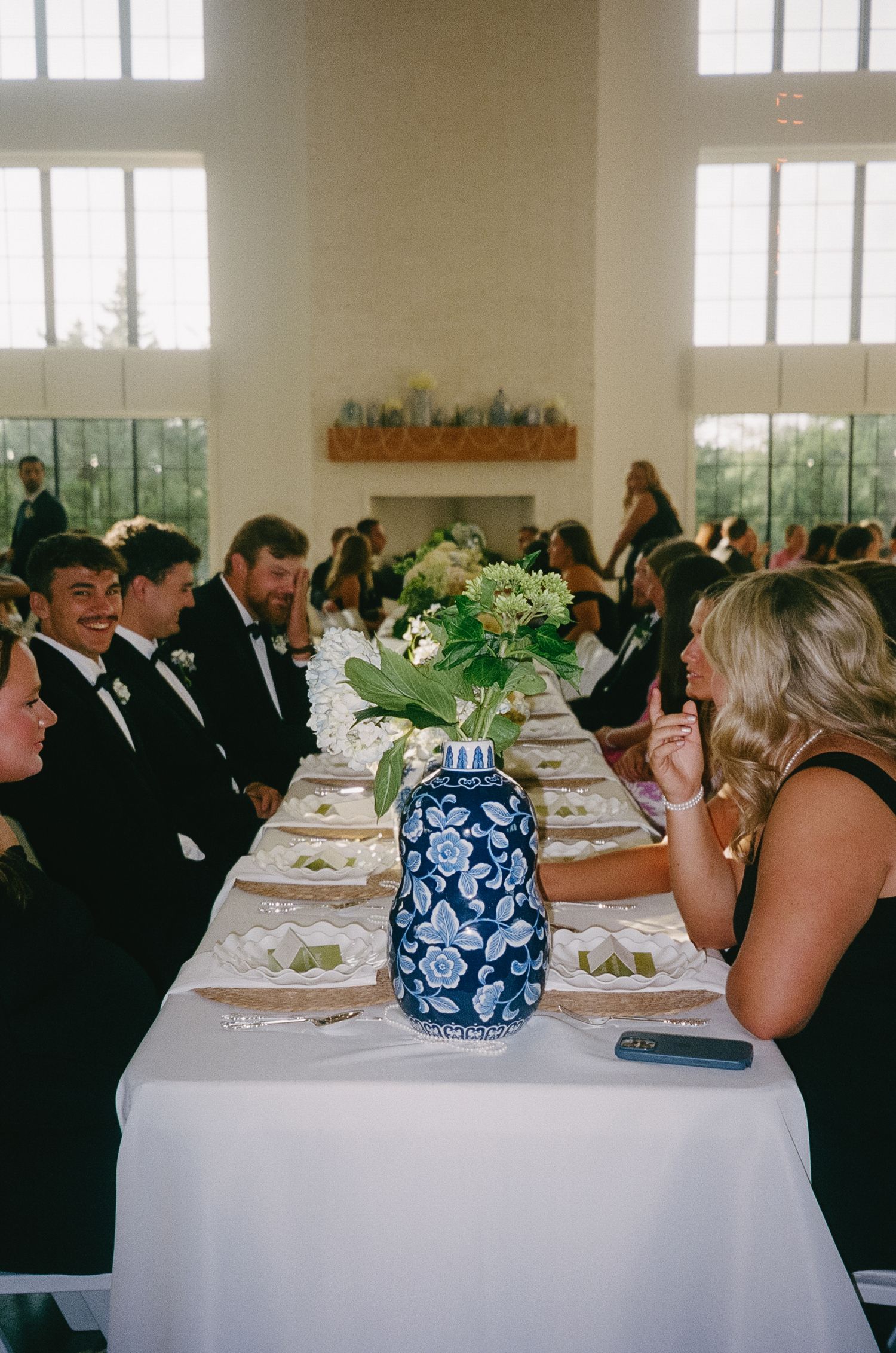 Wedding reception banquet hall with long tables set for dinner and blue and white centerpieces.