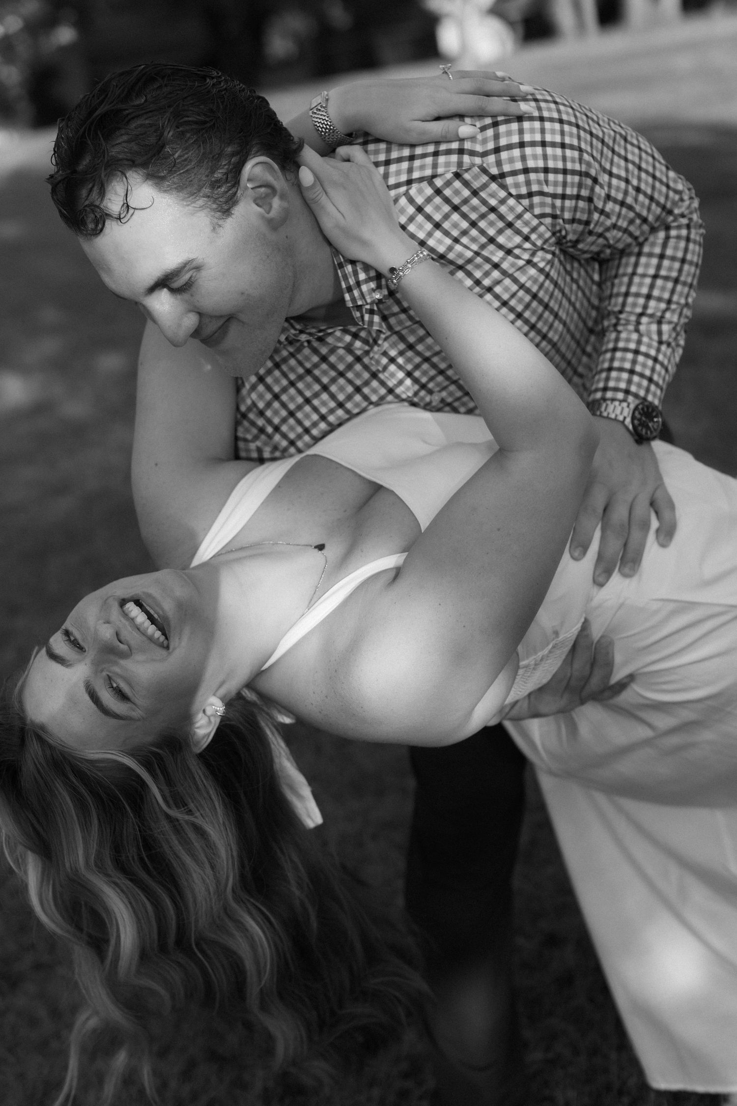A romantic black and white portrait of a couple sharing an intimate moment outdoors.