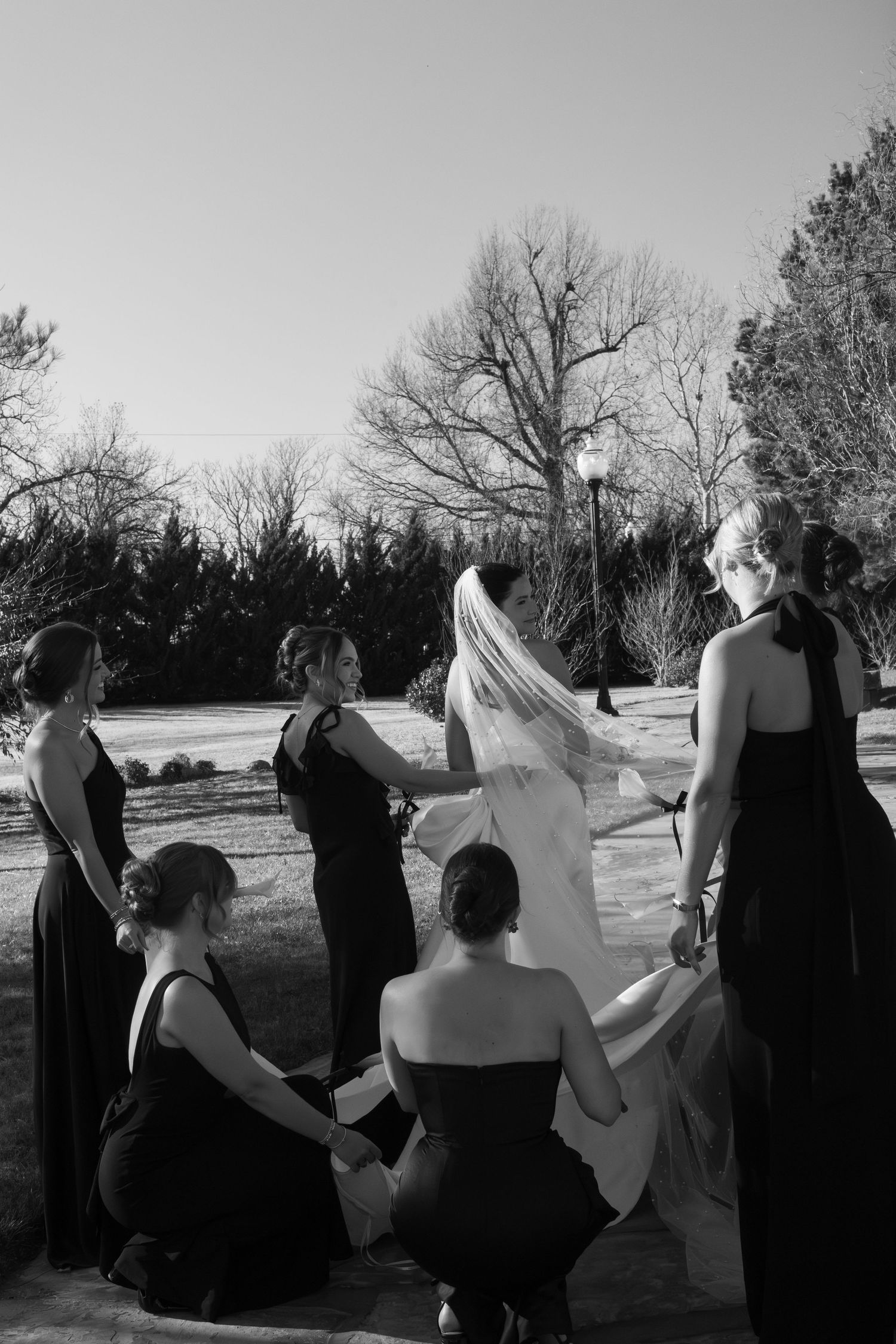 Wedding party in black and white attire dancing and celebrating outdoors.