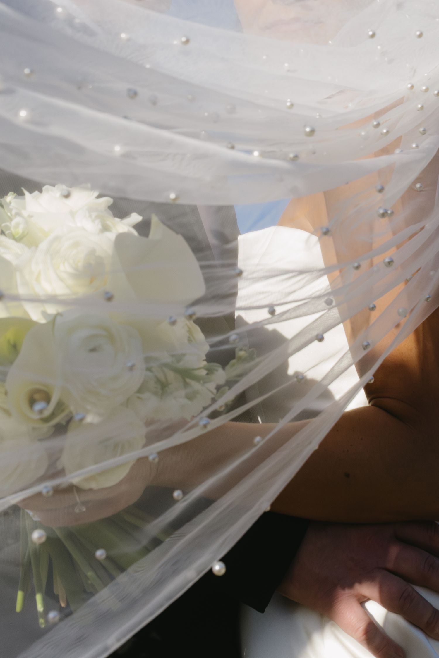 Close-up of delicate white roses and veil details with sparkling embellishments.