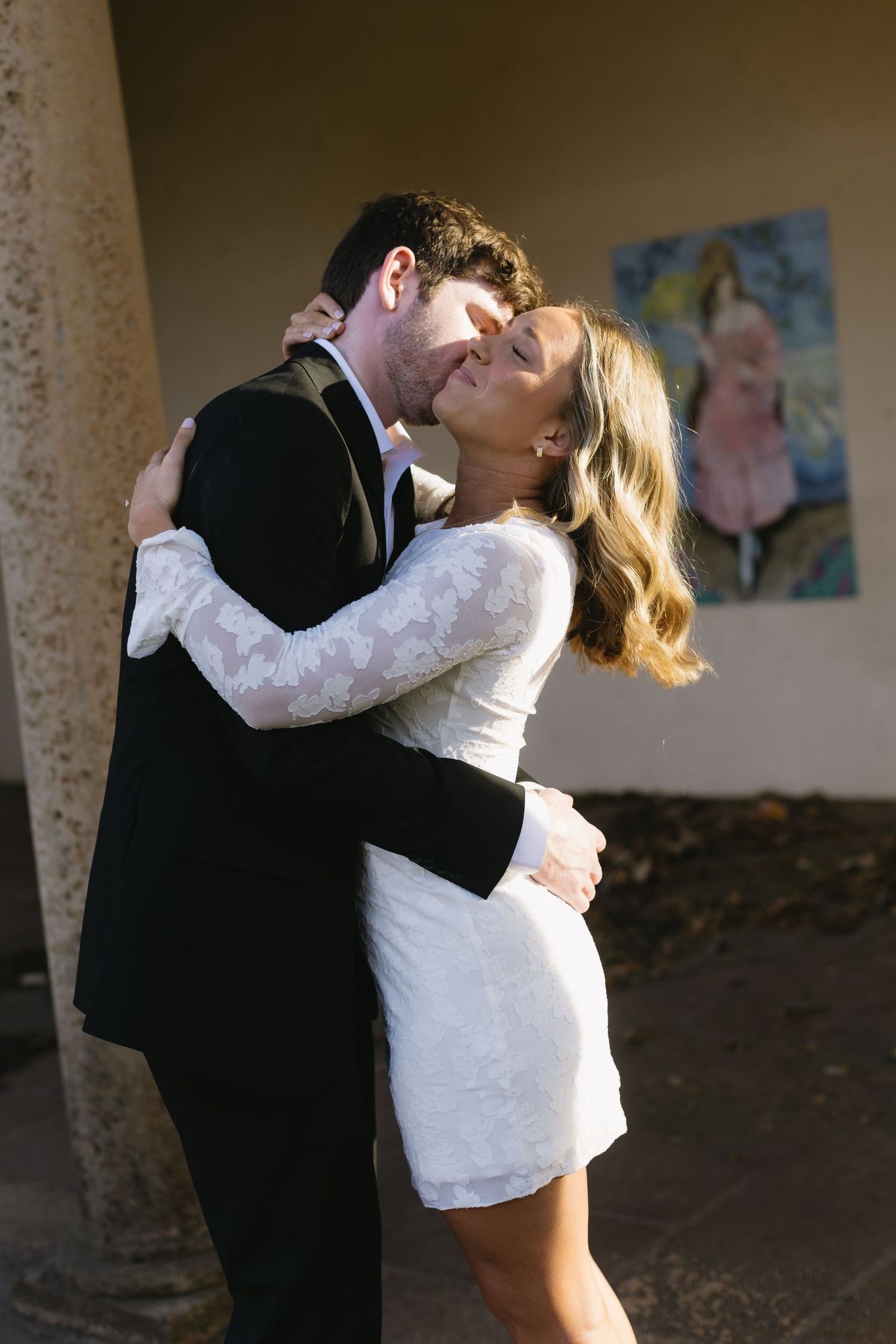 A romantic moment shared between a couple in formal attire beneath an archway.