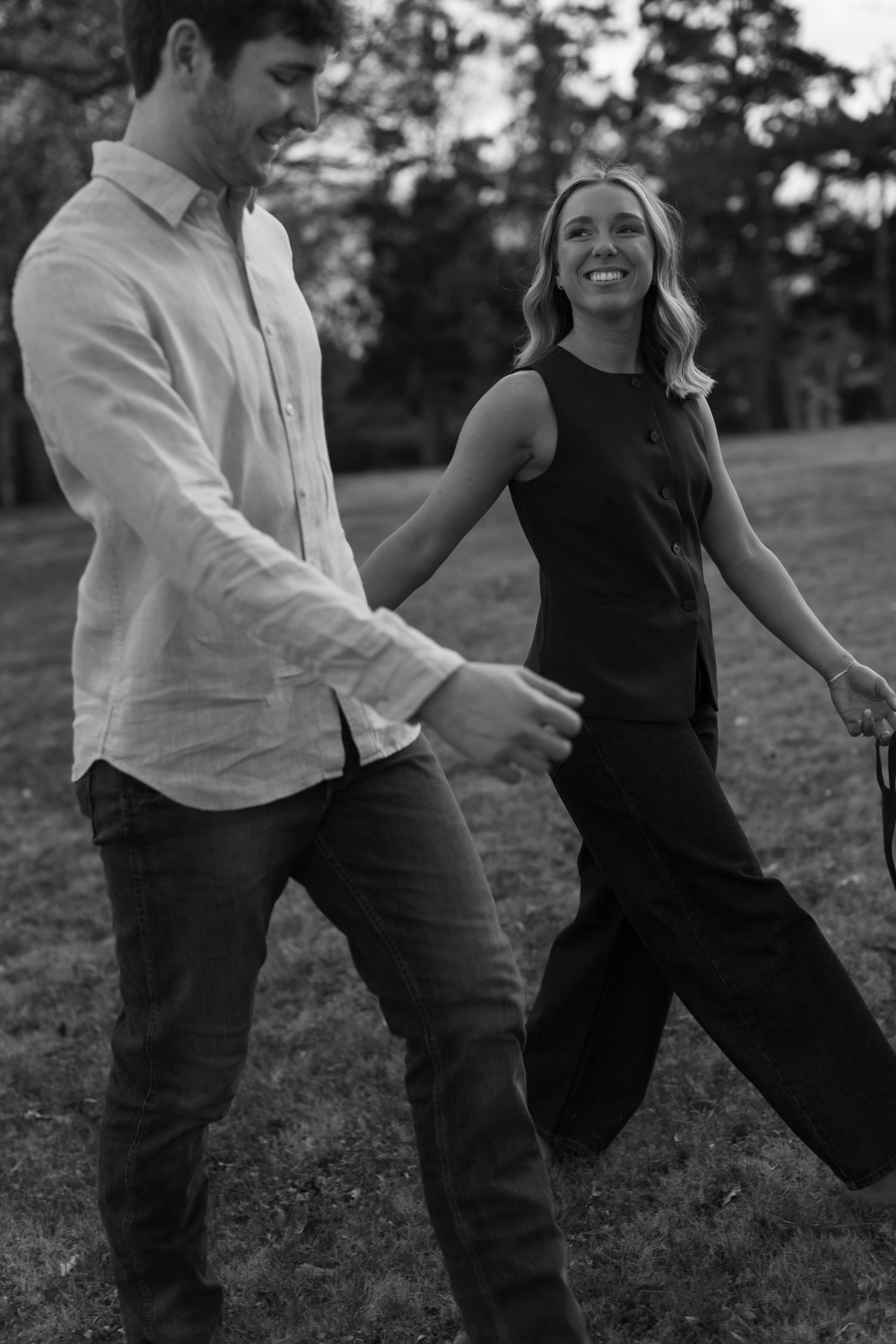 A playful couple dances and laughs together during an outdoor black and white photo session.