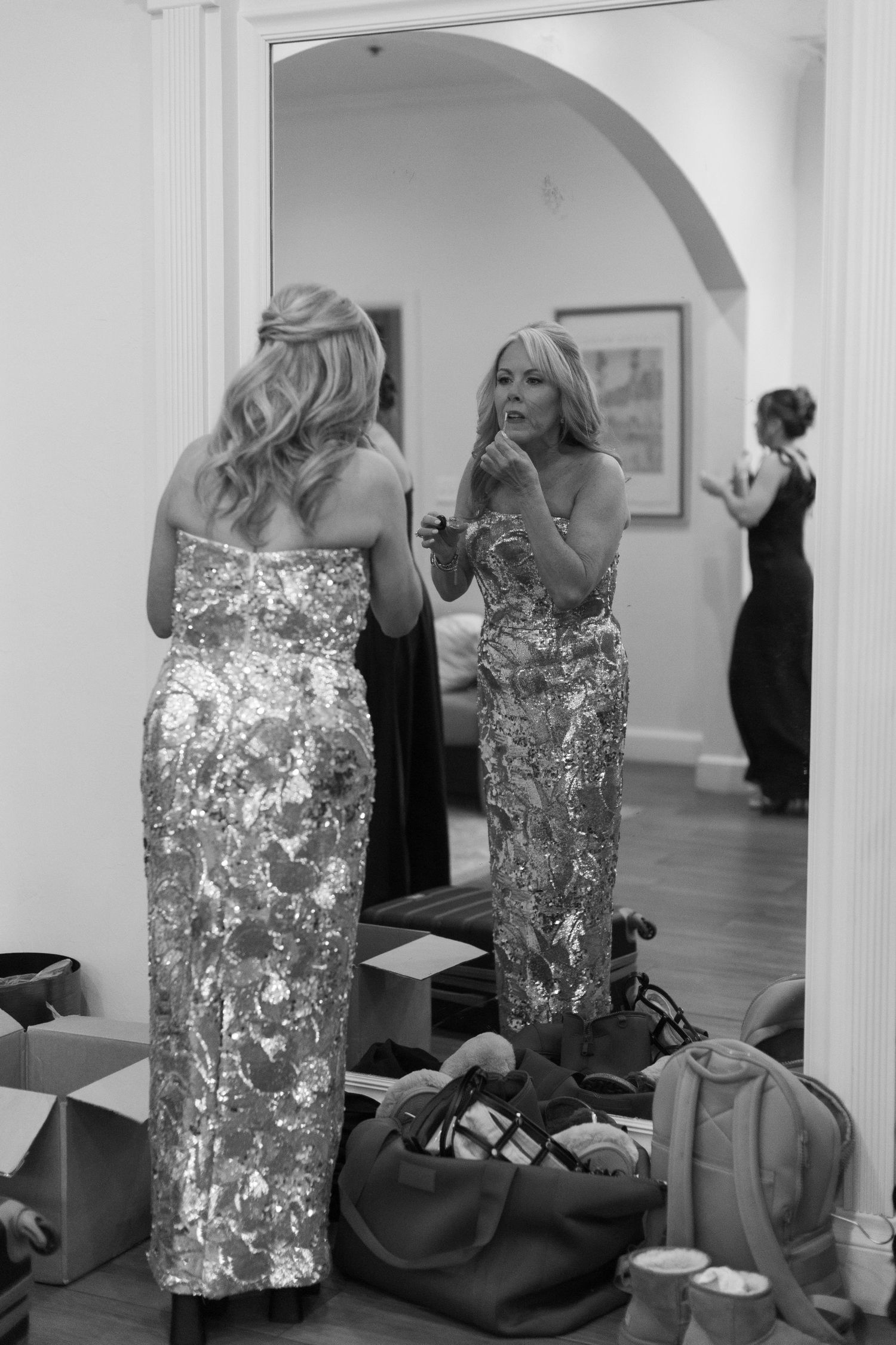 Bridesmaids in sparkly silver dresses getting ready in an art gallery space.