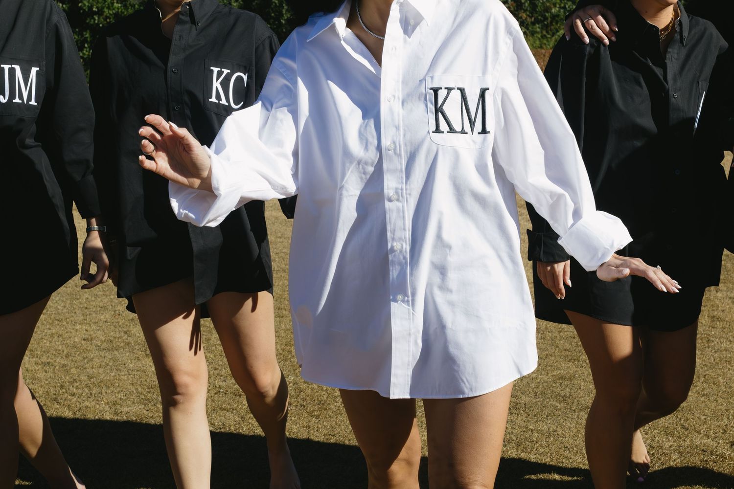 A group of people wearing white and black clothing stand together outdoors in a line formation.