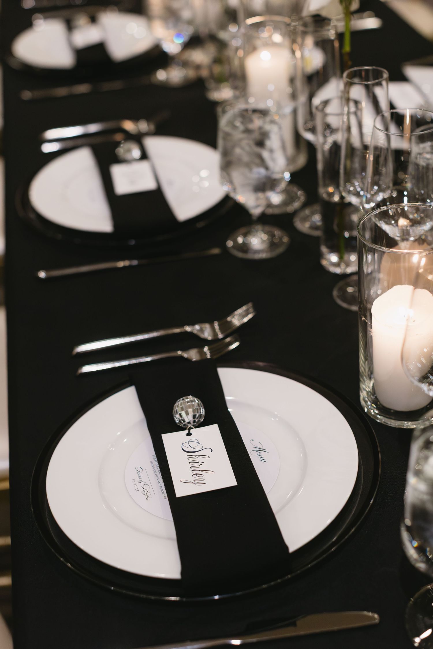 Elegant black and white table settings with candlelight at a formal dinner reception.