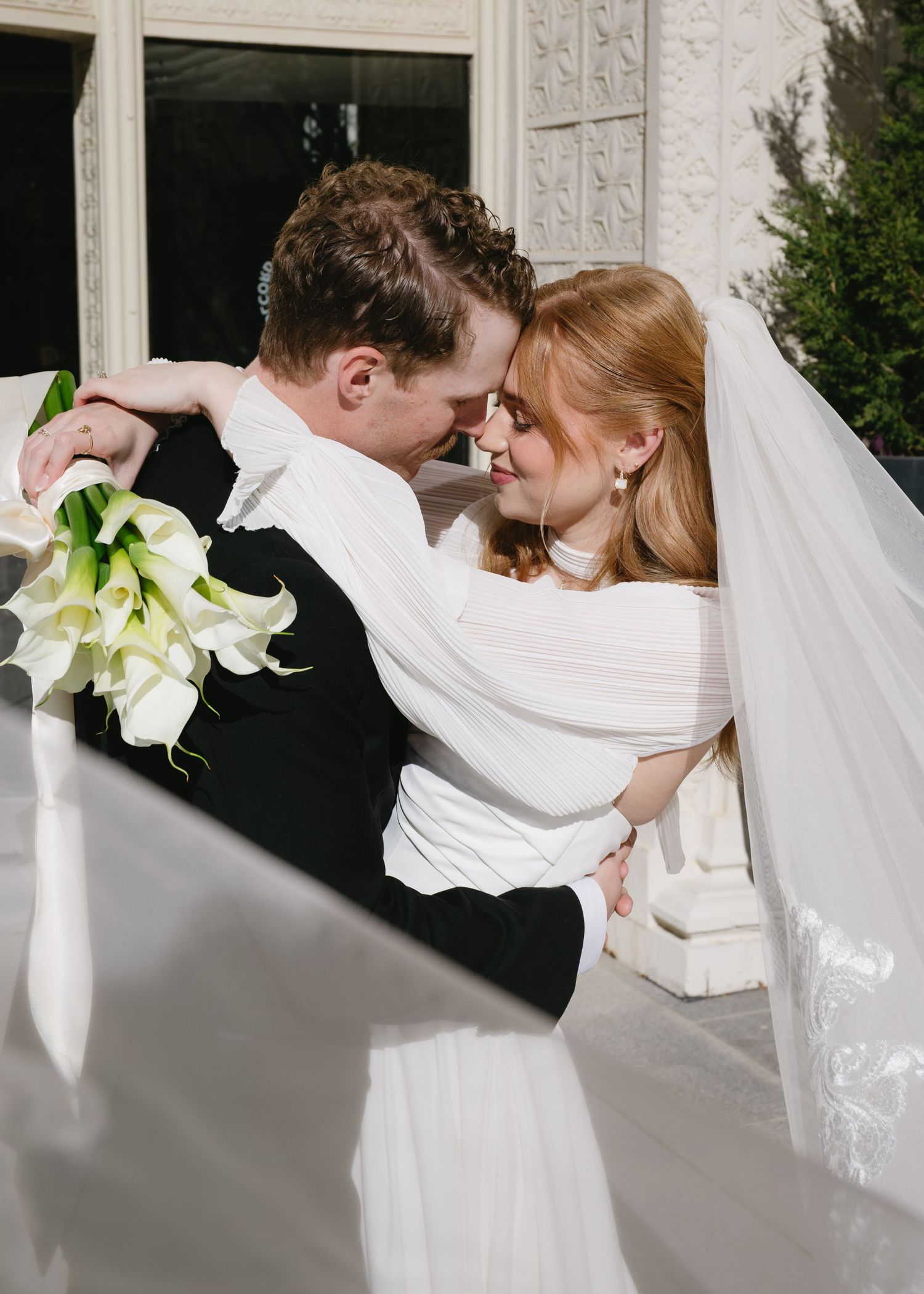 Romantic wedding couple dips in an elegant dance pose with white calla lily bouquet.
