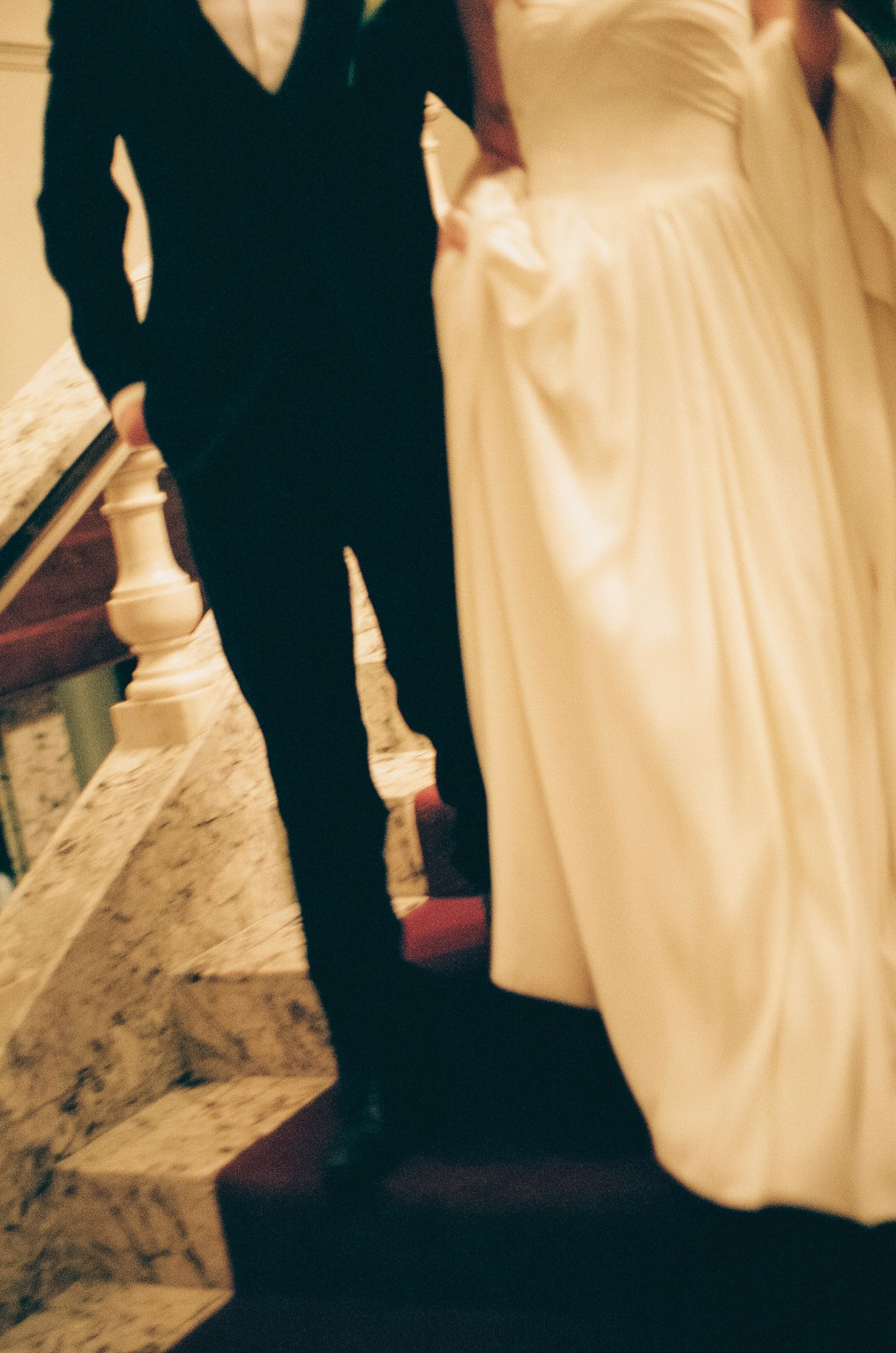 Wedding party silhouettes against warm lighting with flowing white dress details.