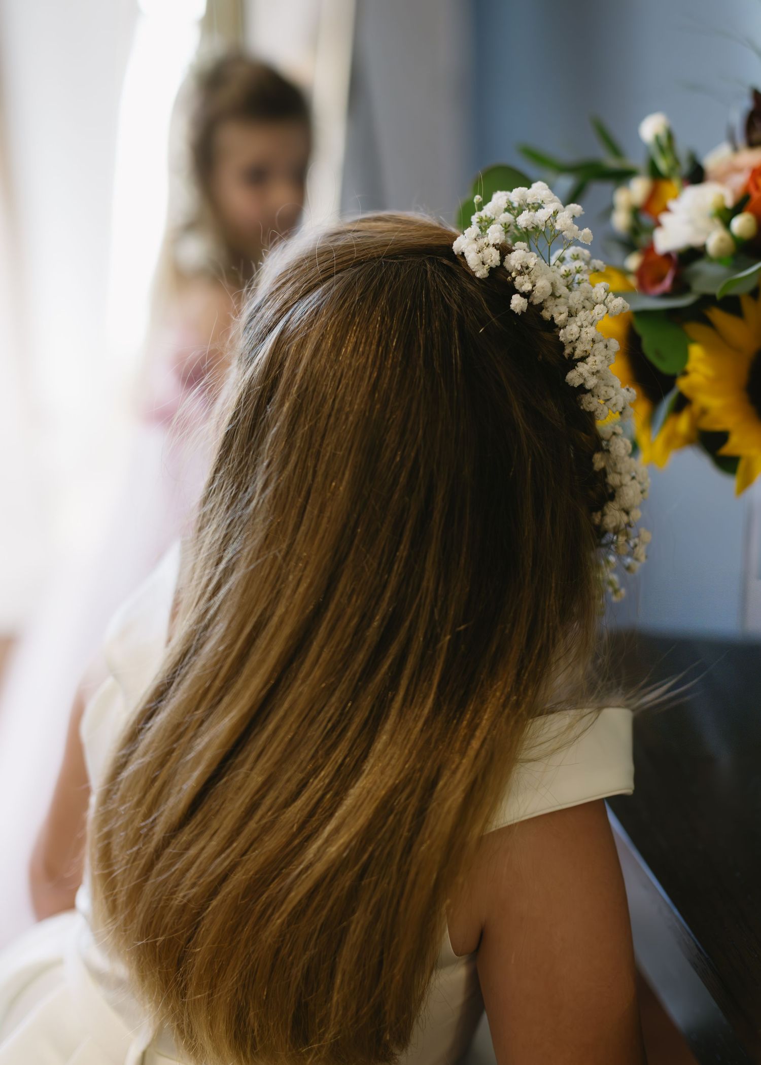 Delicate floral crown adorned with baby's breath and sunflowers on styled hair.