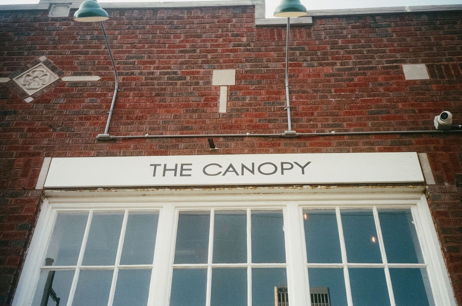 Exterior view of a brick building with multiple storefronts and 'THE CANOPY' signage visible.