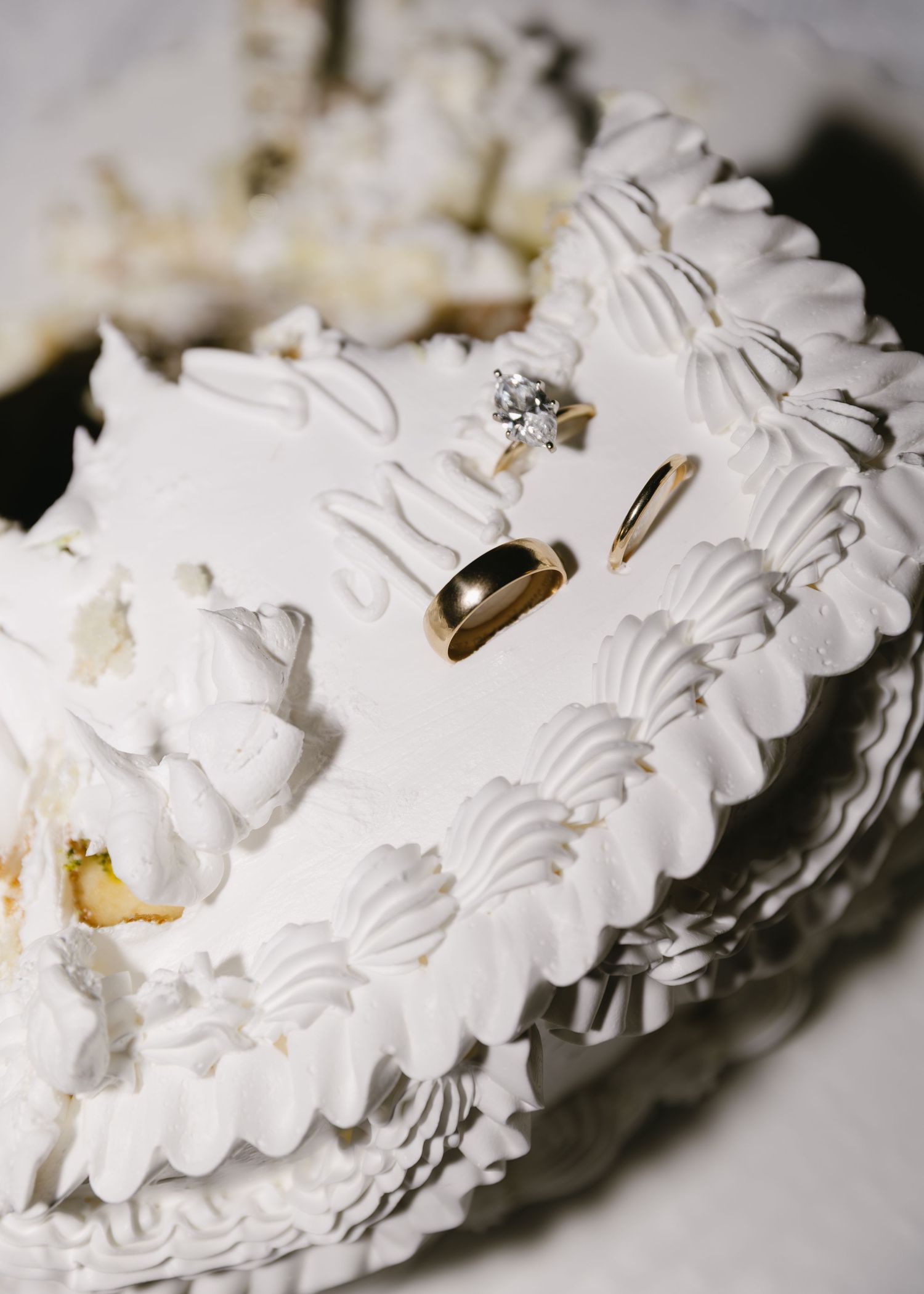 Close-up sequence of wedding rings nestled in delicate white frosting decorations.