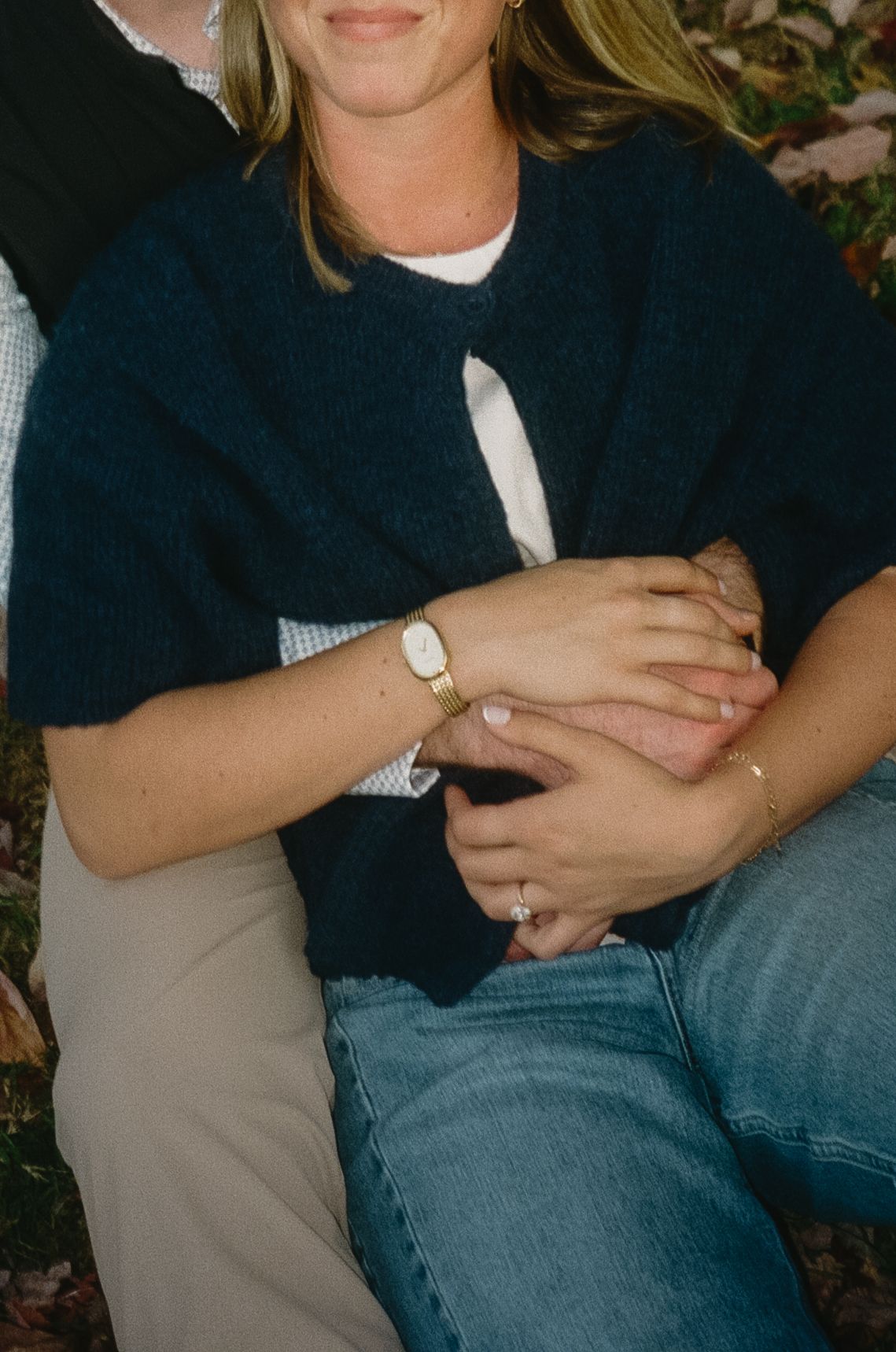A couple sits close together outdoors wearing casual clothing in blue and gray tones.