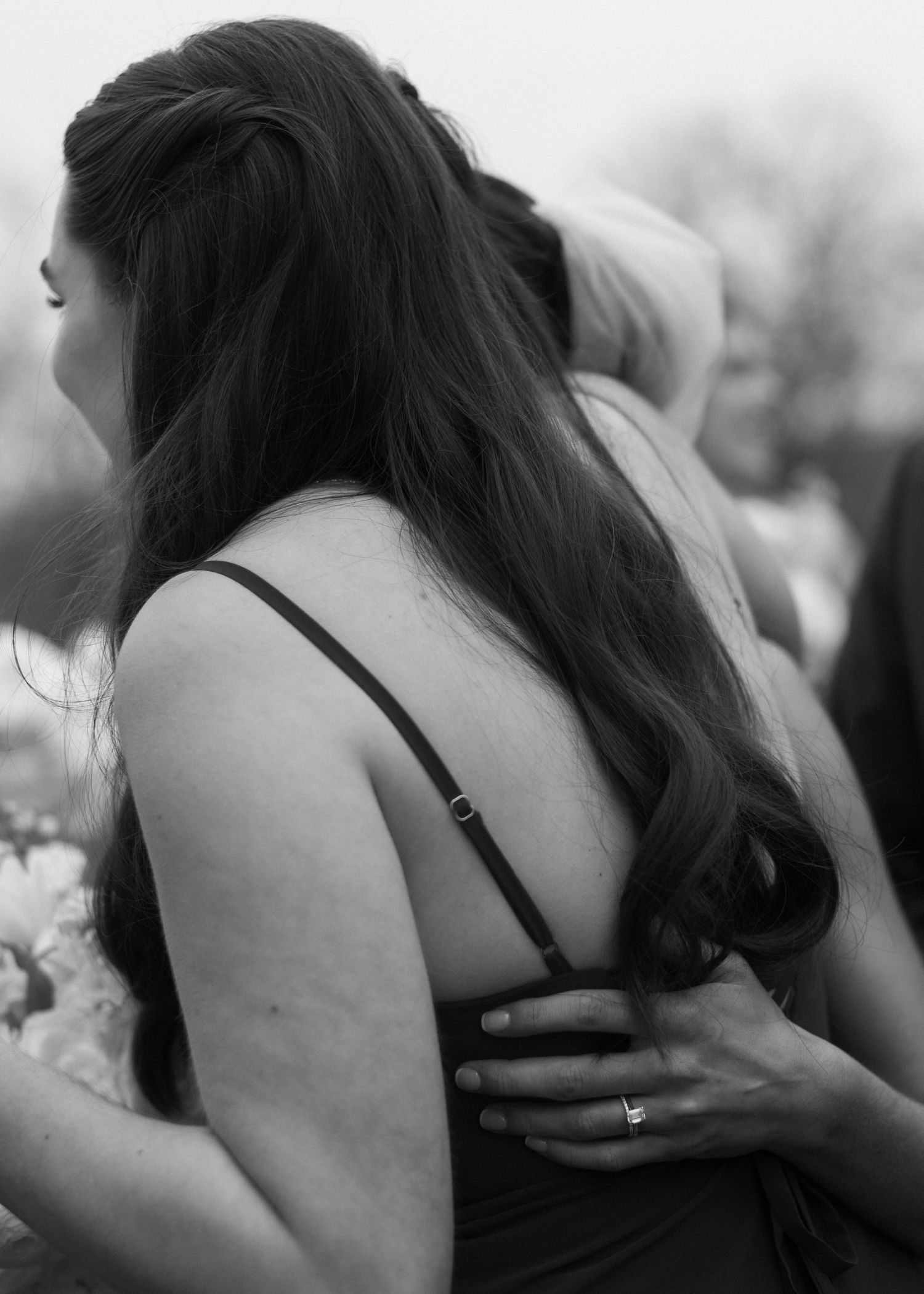 Black and white image of wedding party members embracing in an emotional moment.