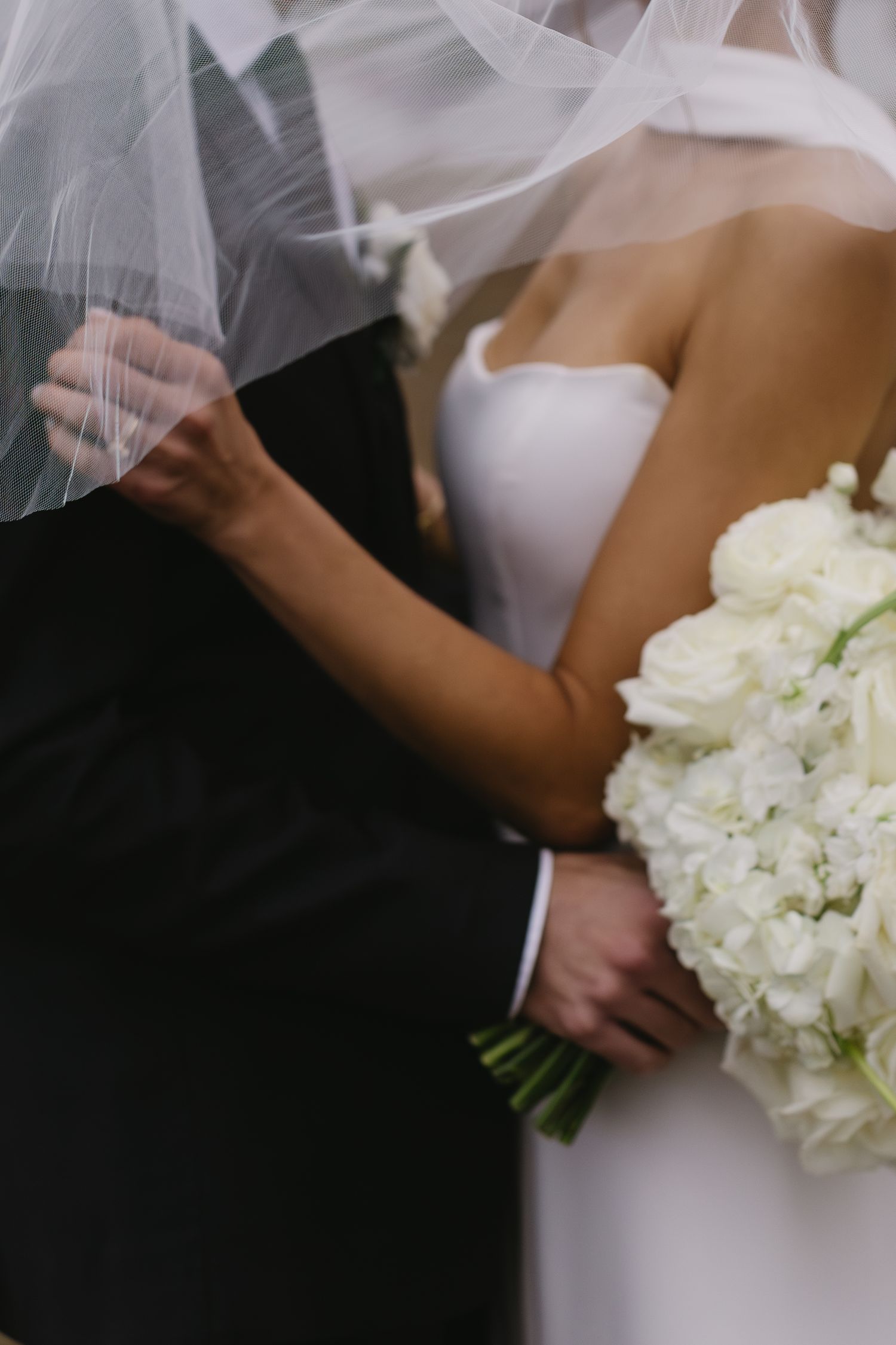 Close-up details of white wedding bouquet and formal attire during ceremony.