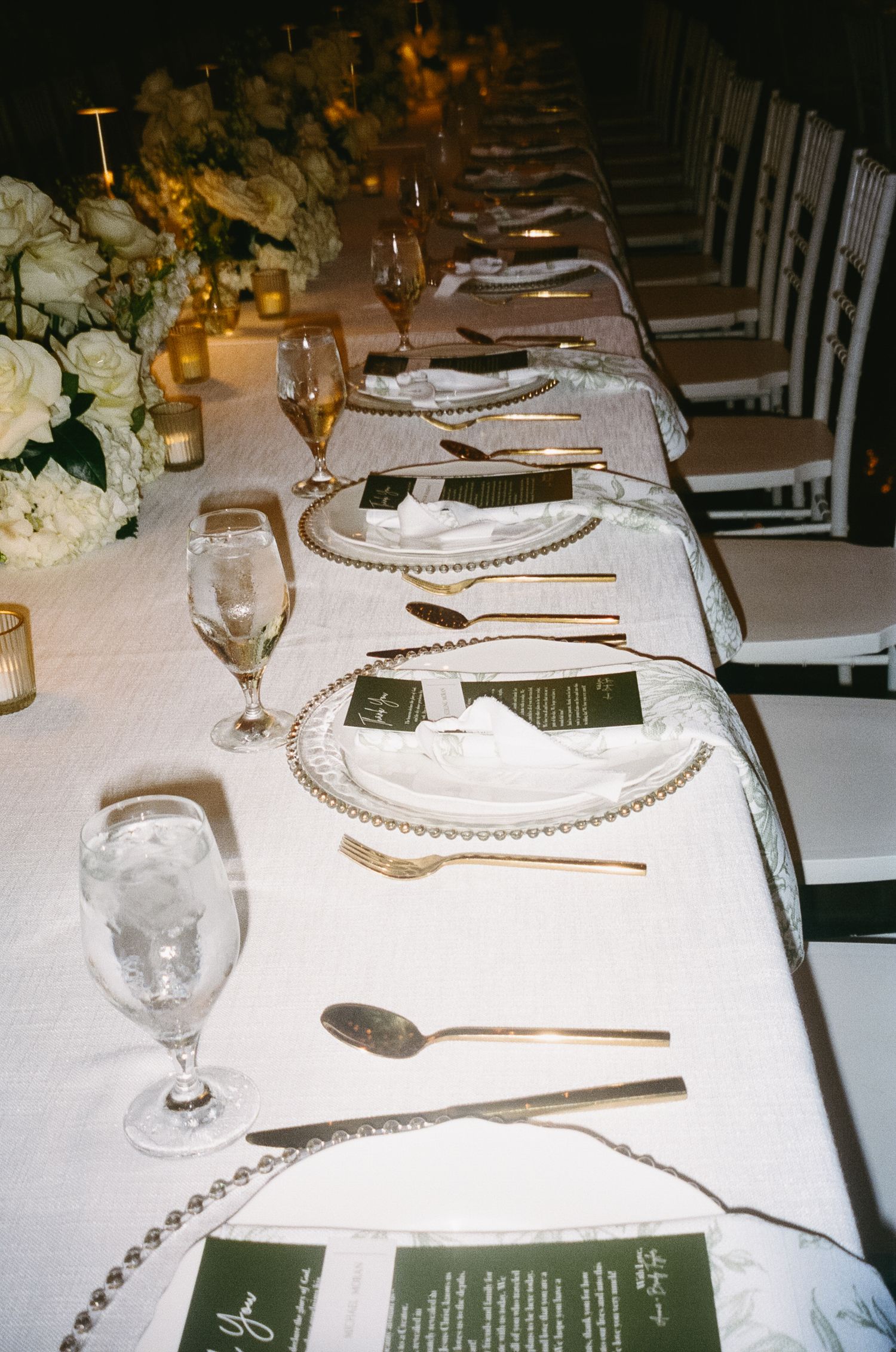 Elegant wedding reception table setting with white linens and crystal glassware.