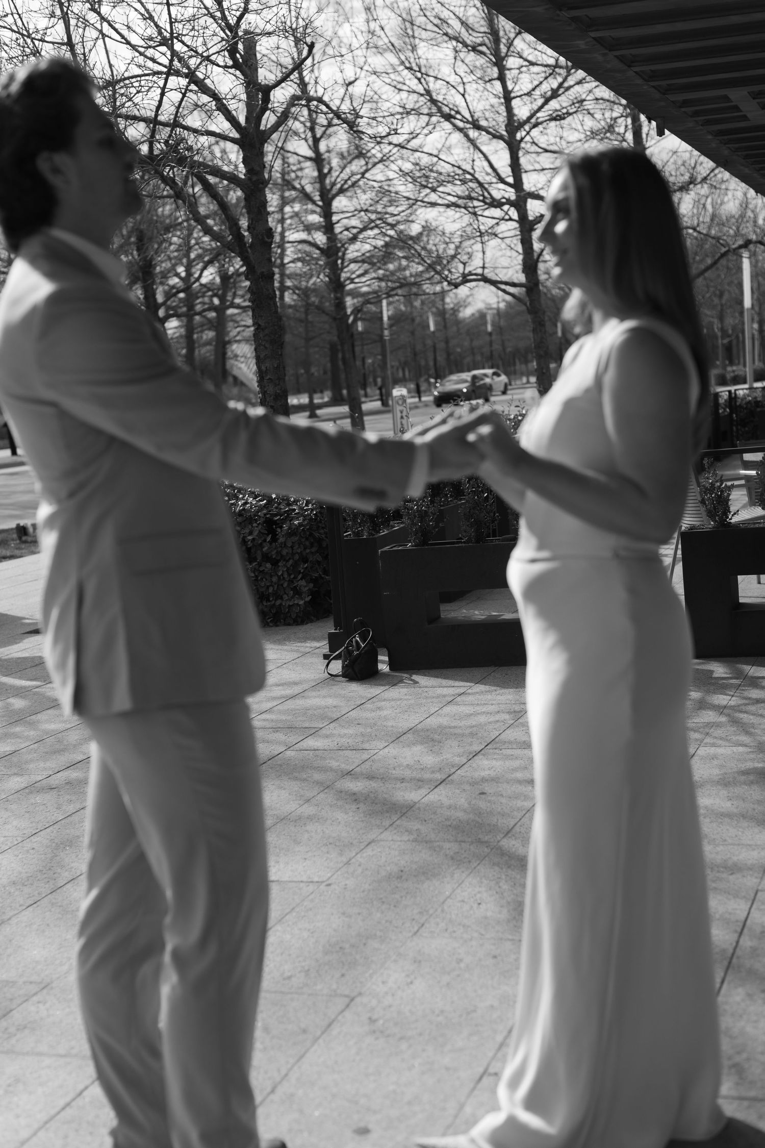 Black and white photo of couple dancing outdoors in formal attire.