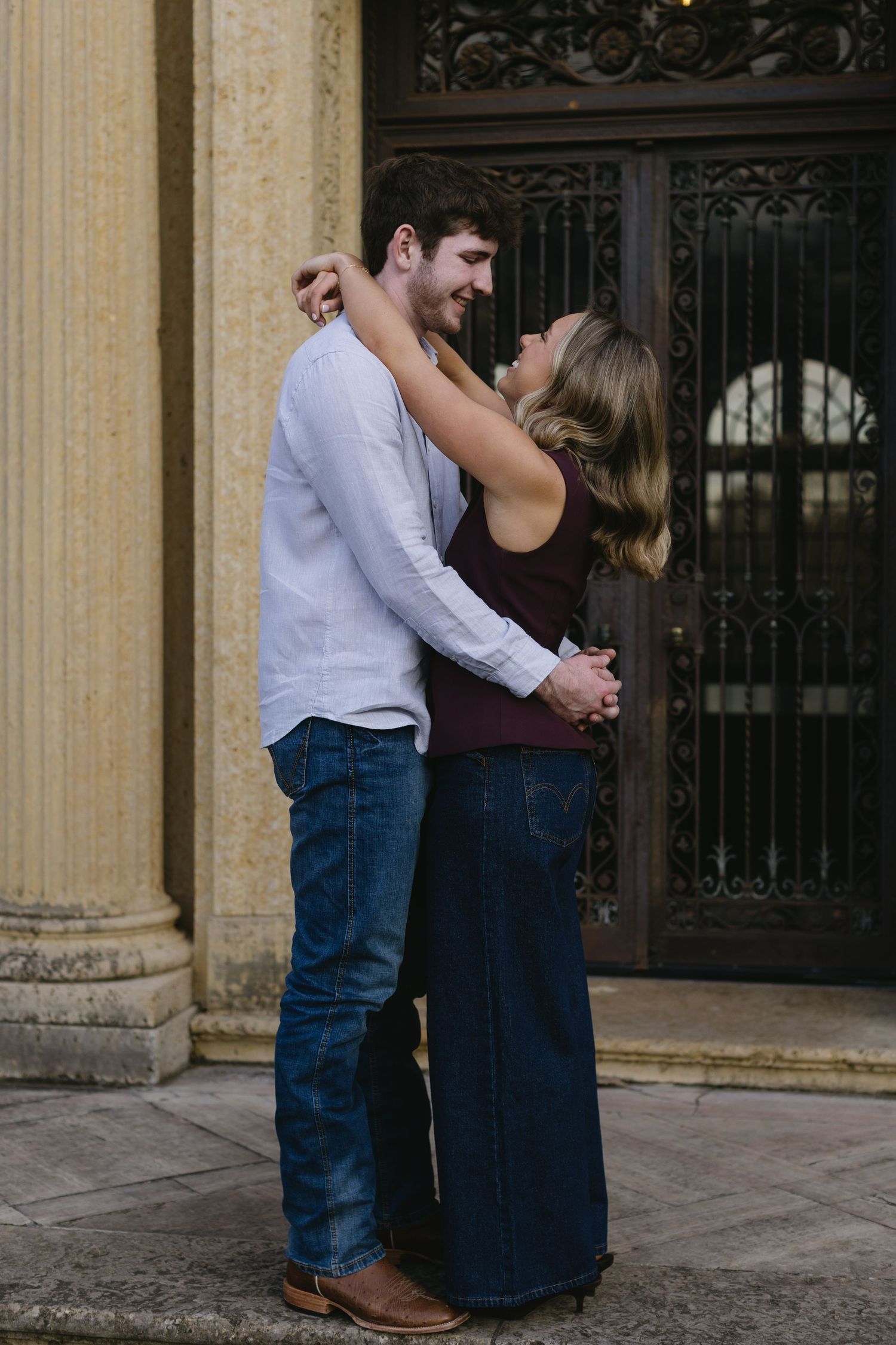 A couple shares a tender moment near ornate architectural columns.