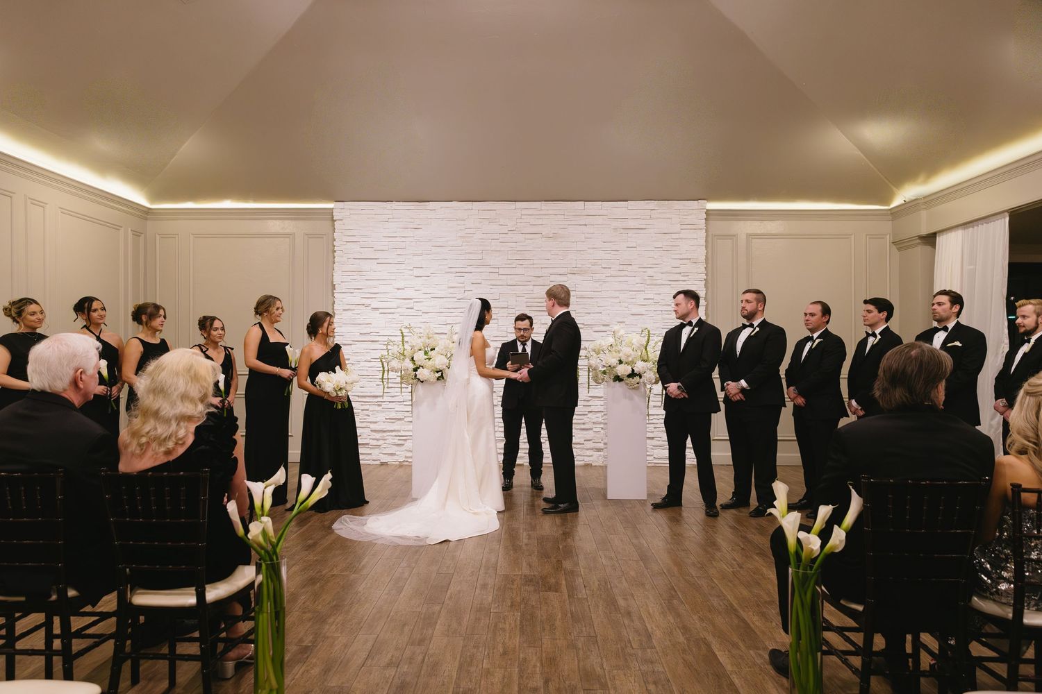 Wedding ceremony setup in modern indoor venue with white brick walls and wooden floors.