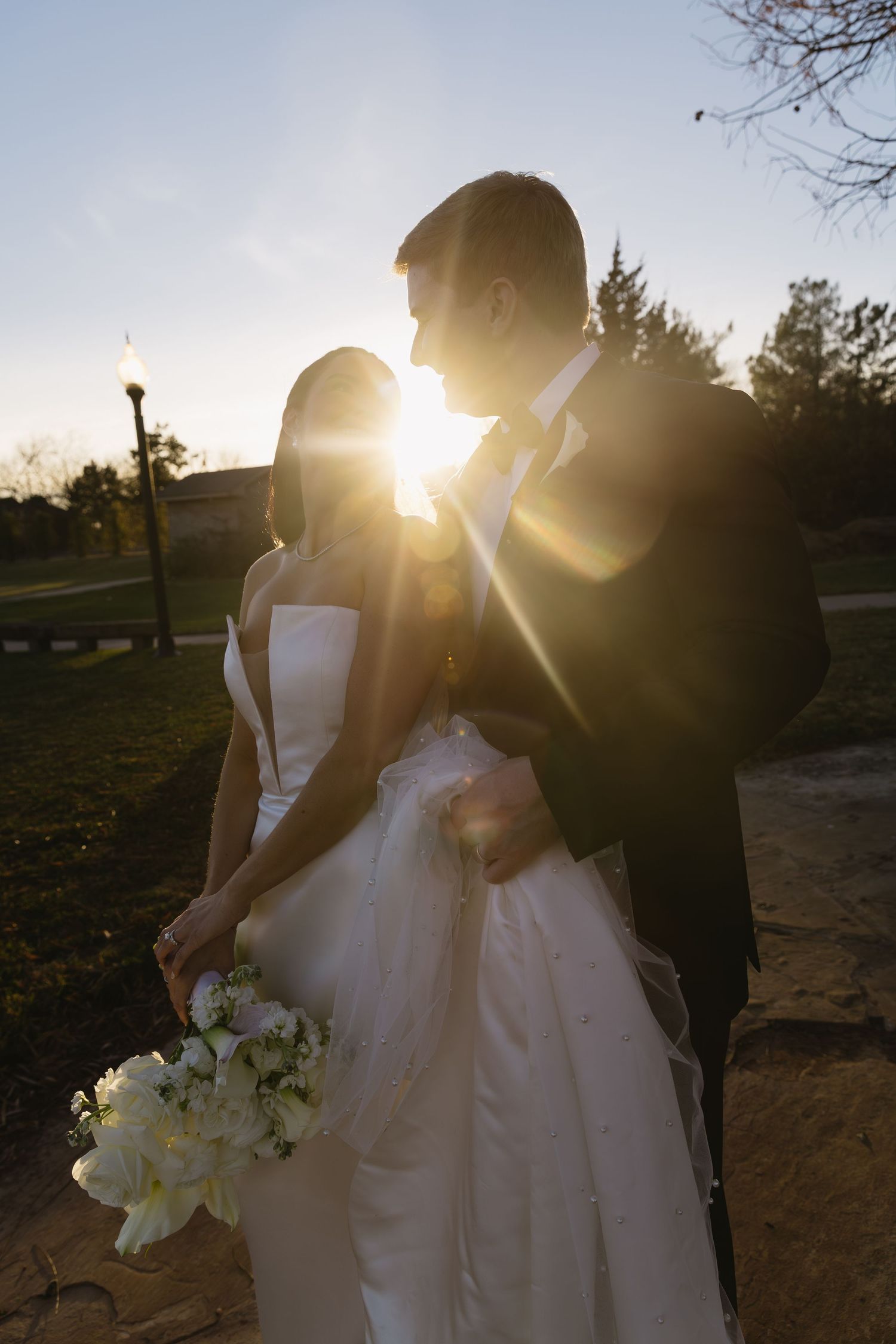 Golden sunset light illuminates a romantic wedding portrait session outdoors.