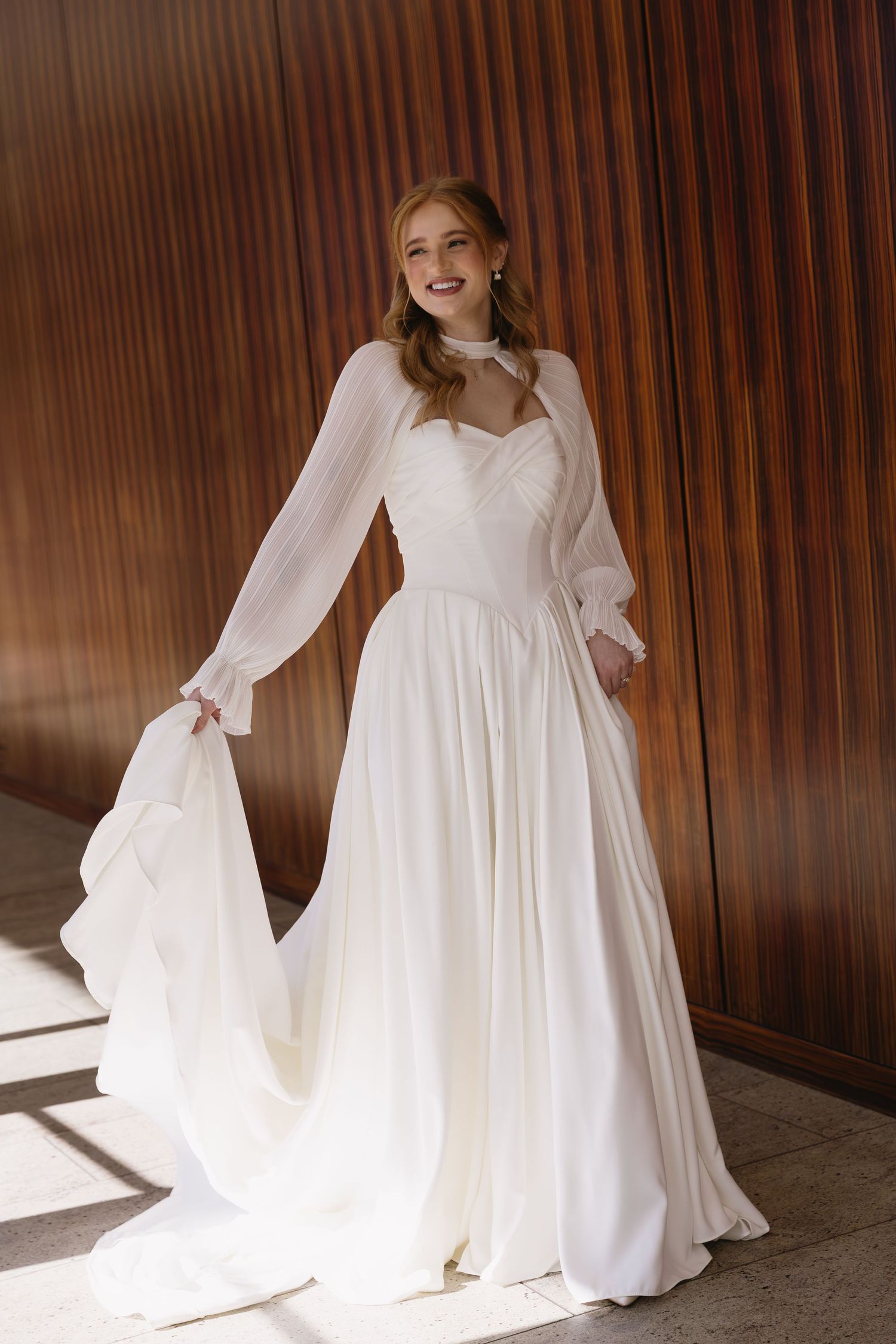 A white wedding gown with flowing sleeves captured in dynamic poses against wood paneling.