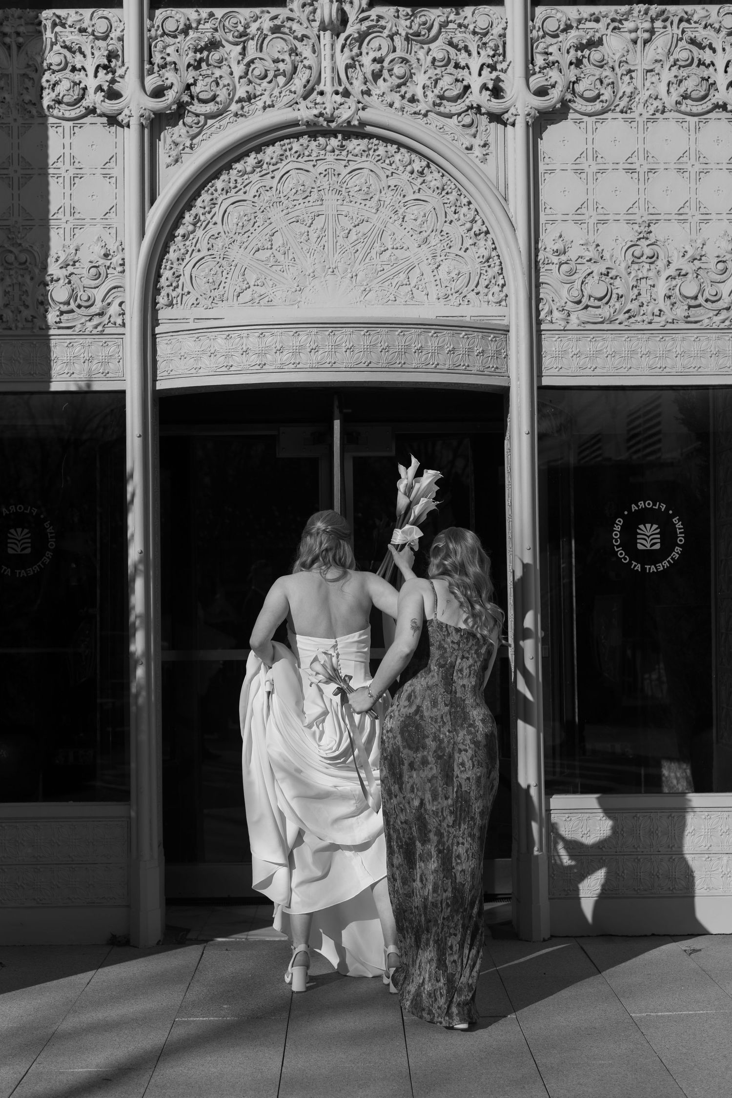 Wedding party walking under ornate architectural details in black and white photography.
