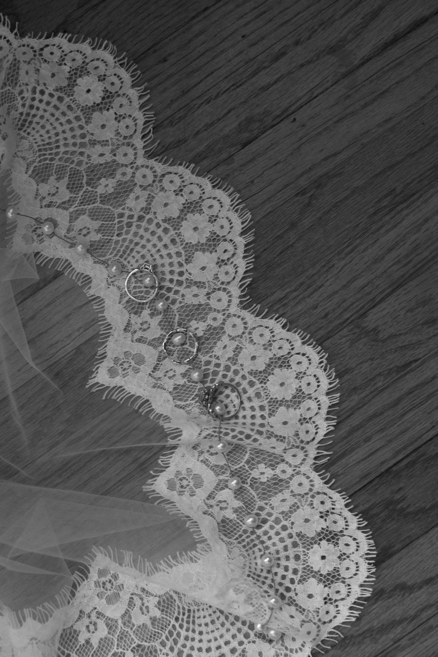 Delicate white lace trim with scalloped edges and floral pattern details against a dark wooden surface.
