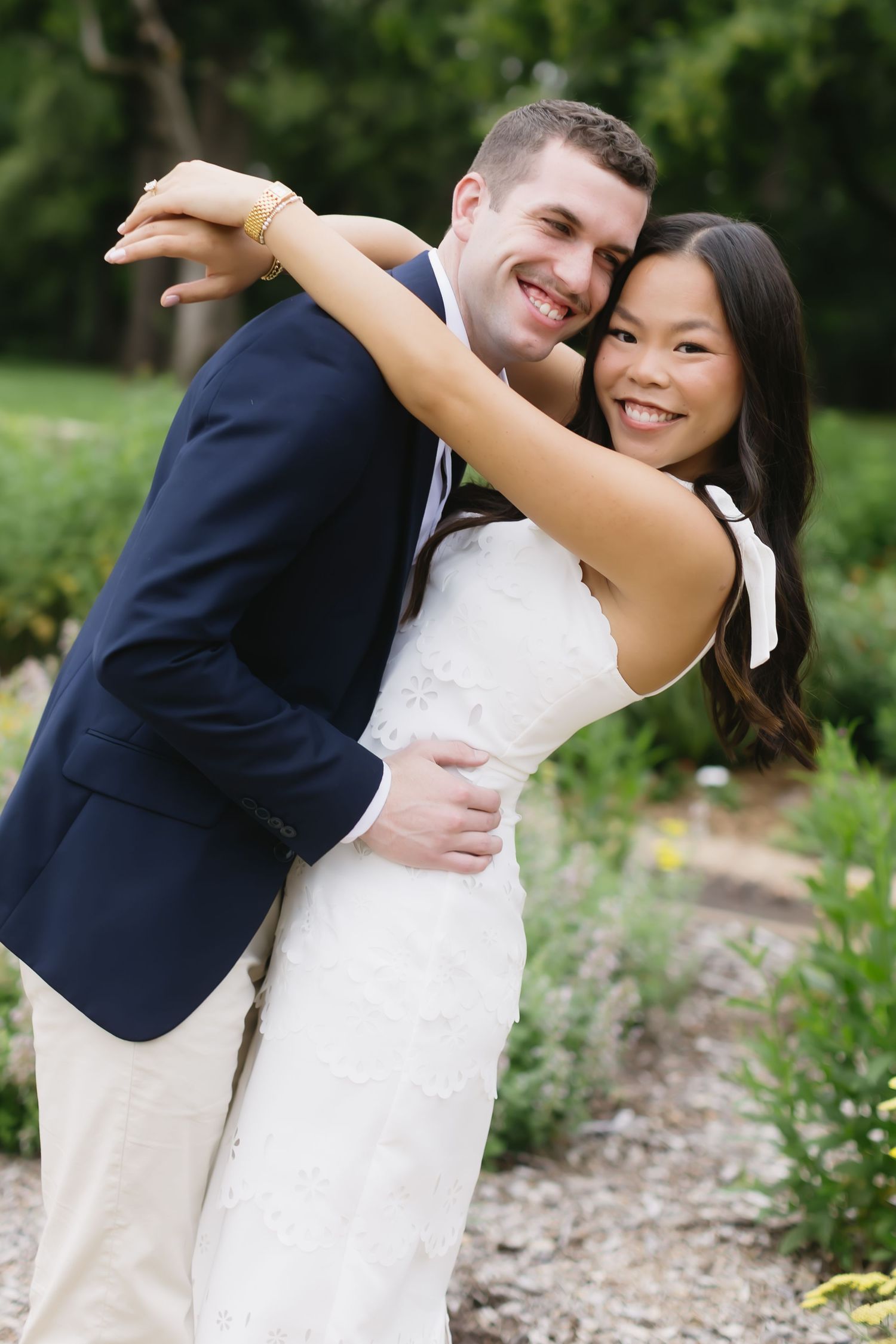 A couple in wedding attire sharing romantic dance poses in a garden setting with lush greenery.