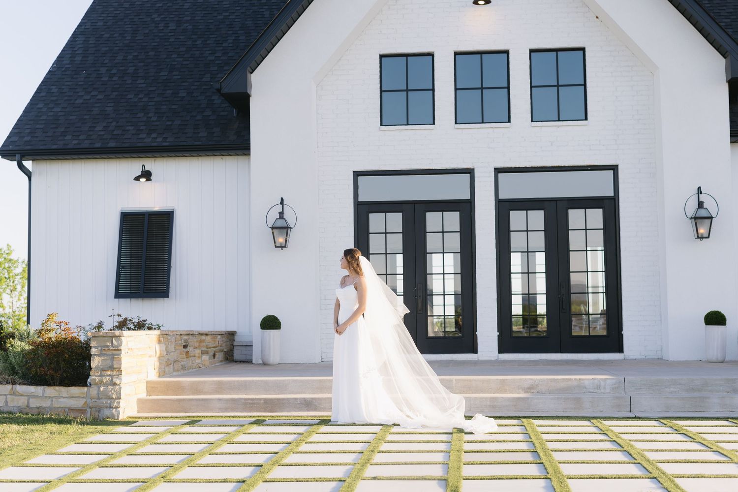 Modern farmhouse exterior featuring black and white color scheme with large windows and geometric walkway pattern.