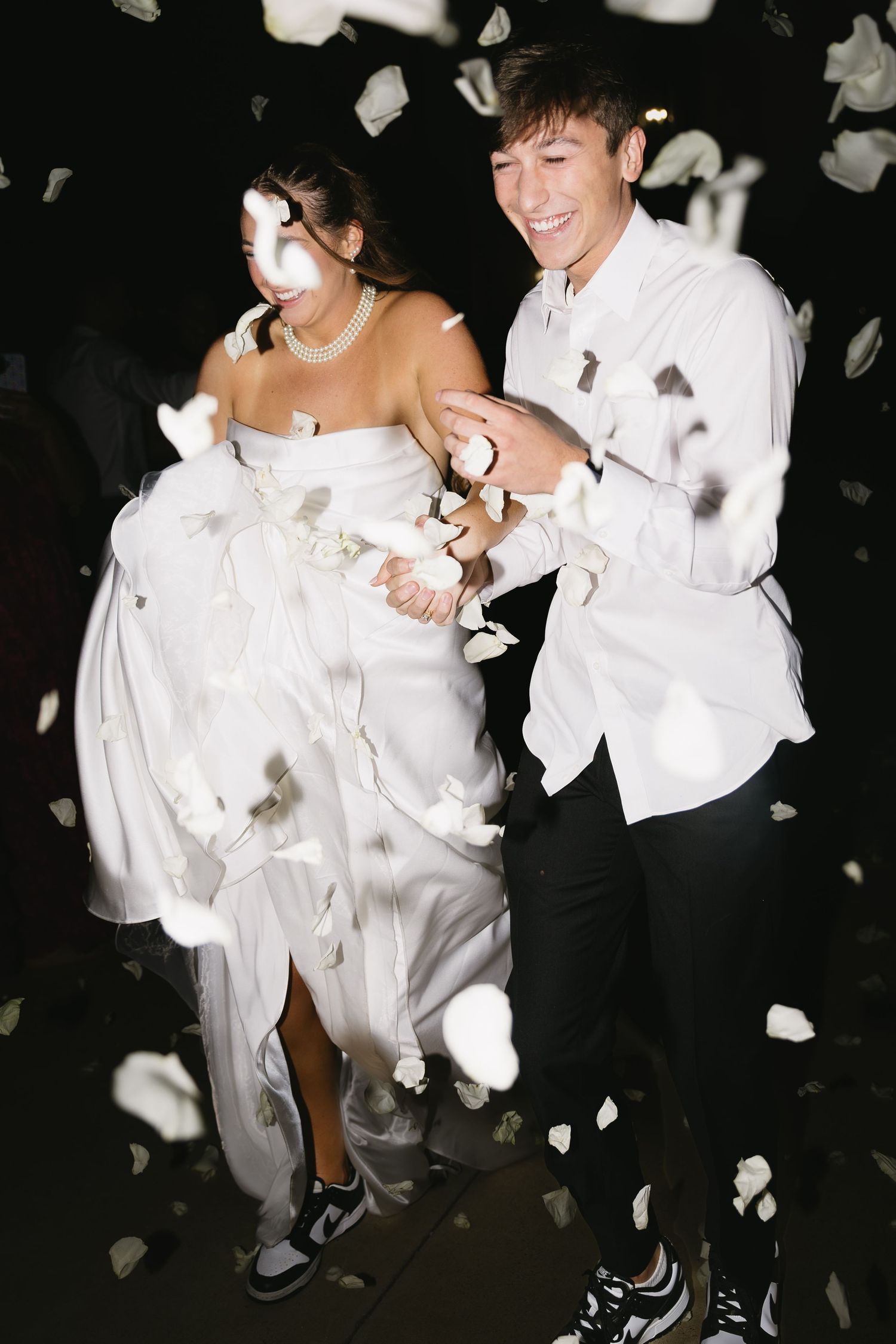 White flower petals falling around dancing figures in formal wedding attire.