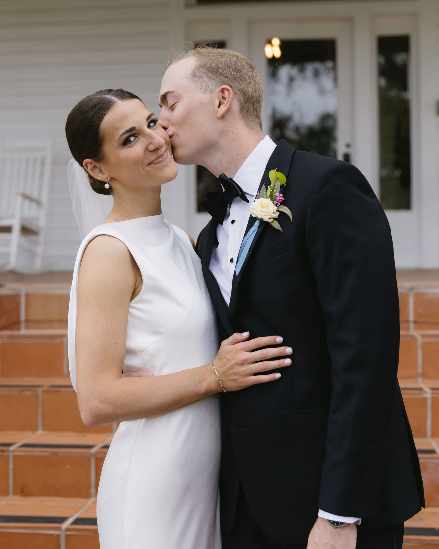 A tender moment shared between newlyweds at their wedding with the bride in white and groom in black tuxedo.