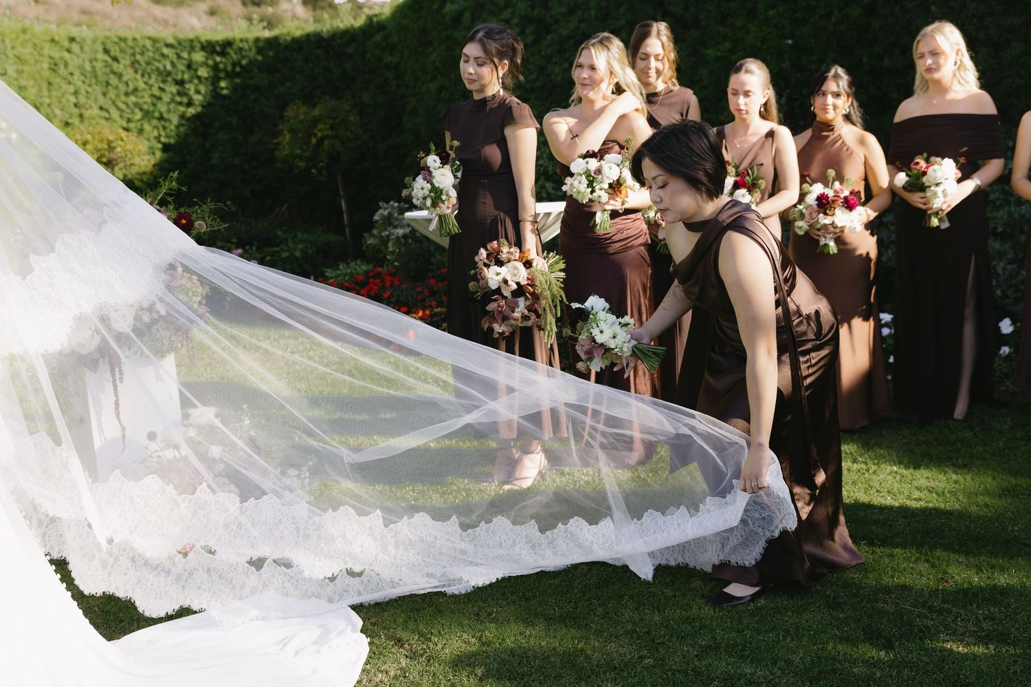 A flowing white wedding veil catches the sunlight during an outdoor ceremony.