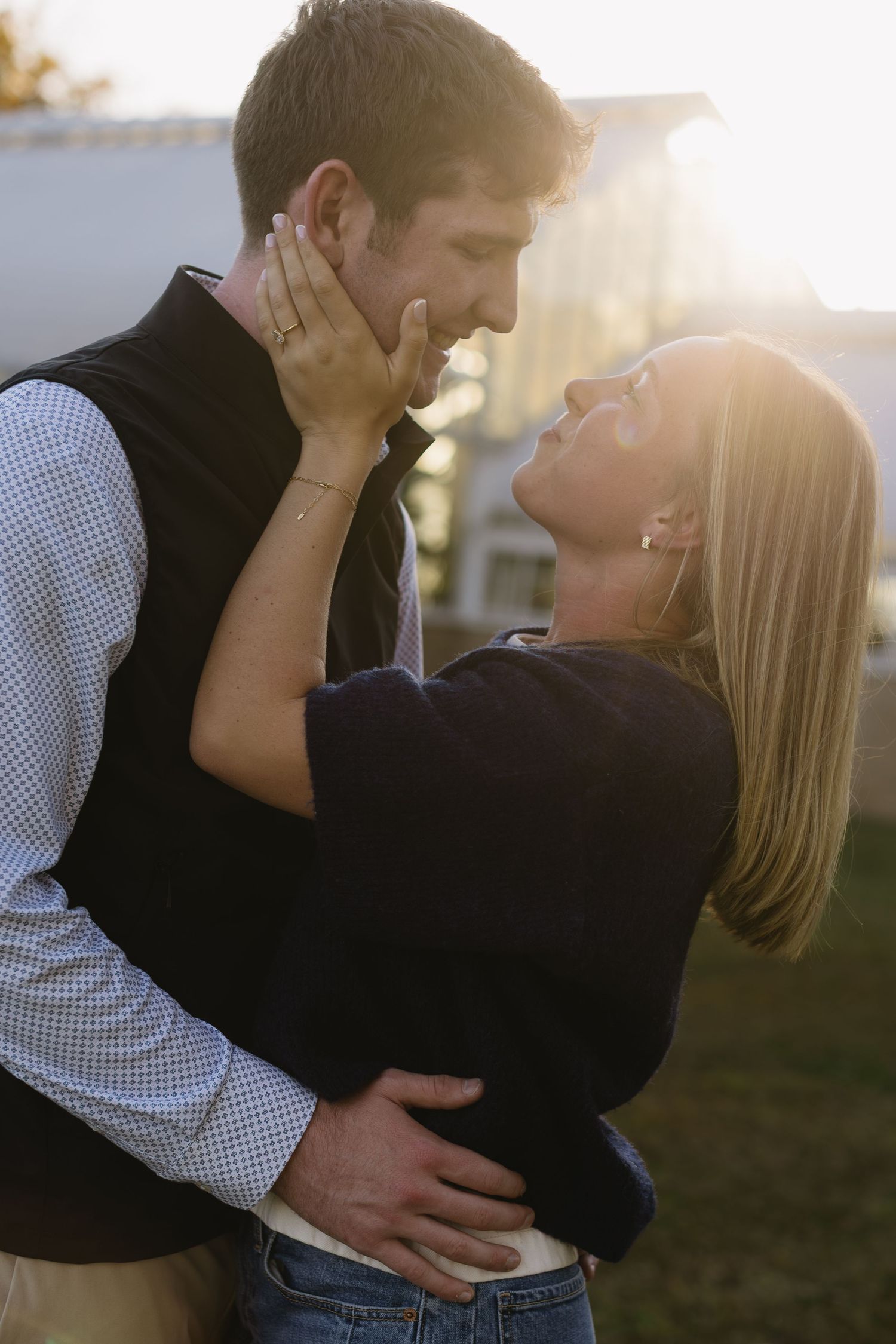 A romantic couple embracing in golden sunlight during sunset outdoors.