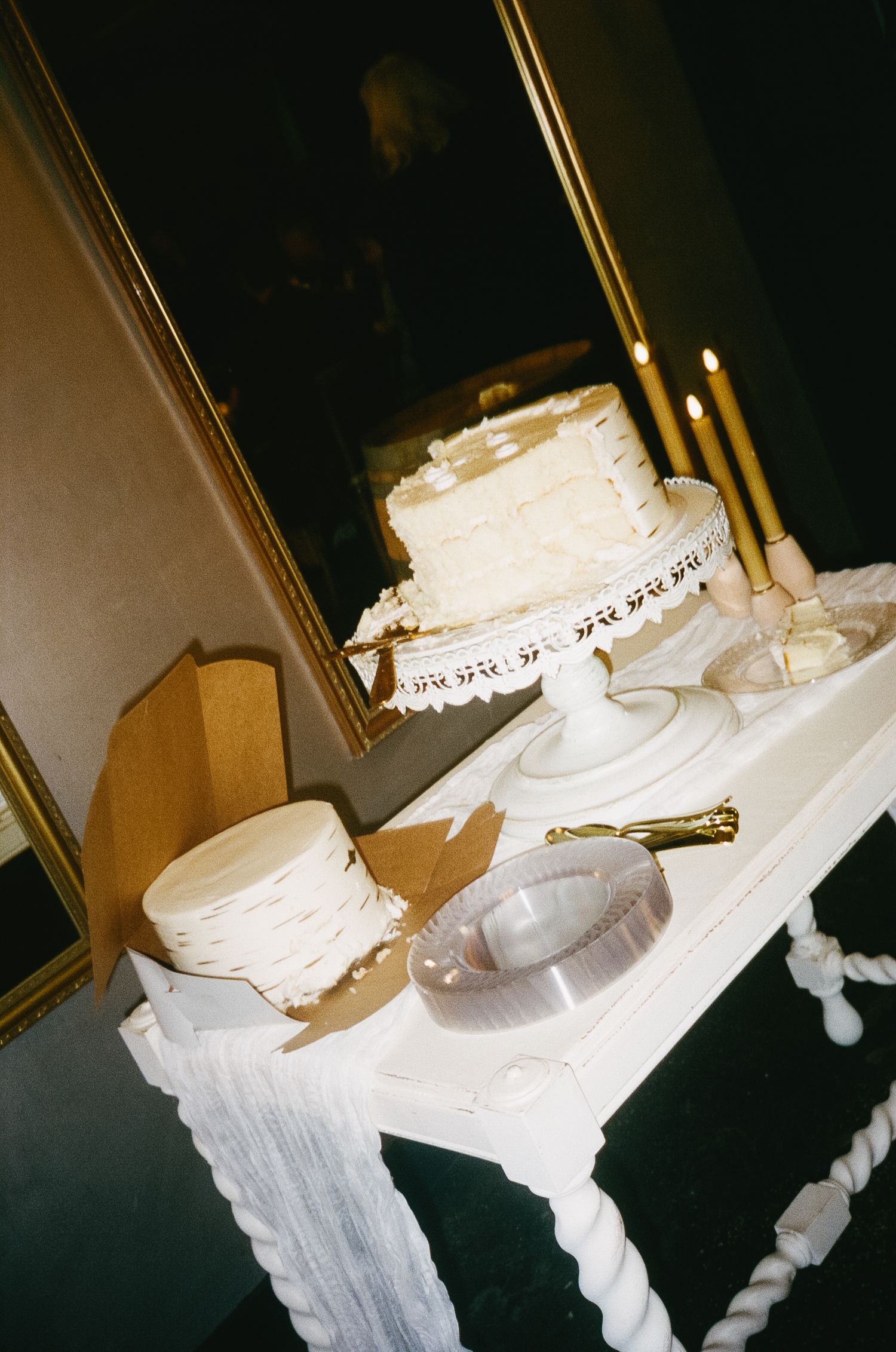 White tiered wedding cake displayed under dramatic lighting at an evening reception.