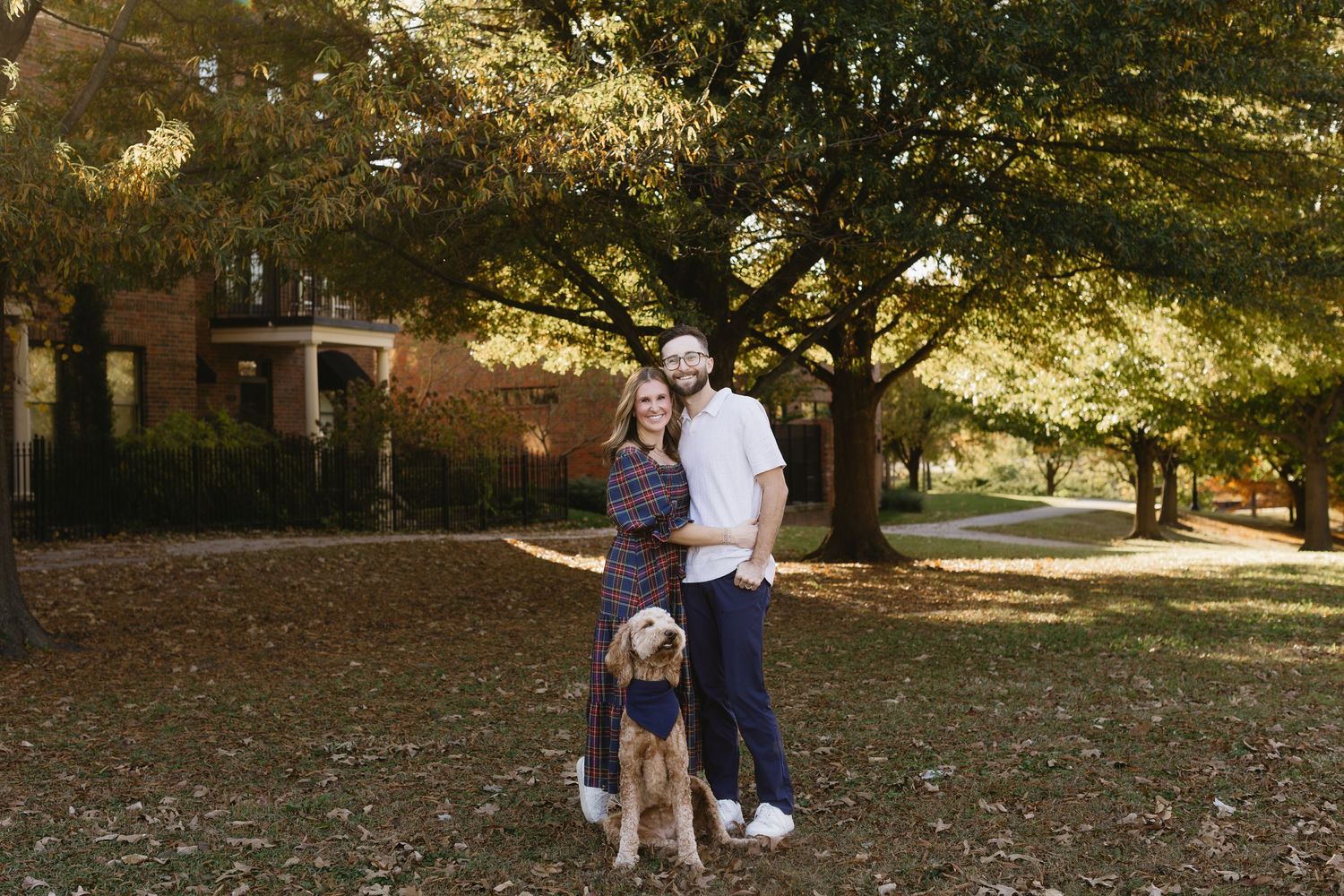 Two people walk together in a park on an autumn day with golden sunlight filtering through trees.