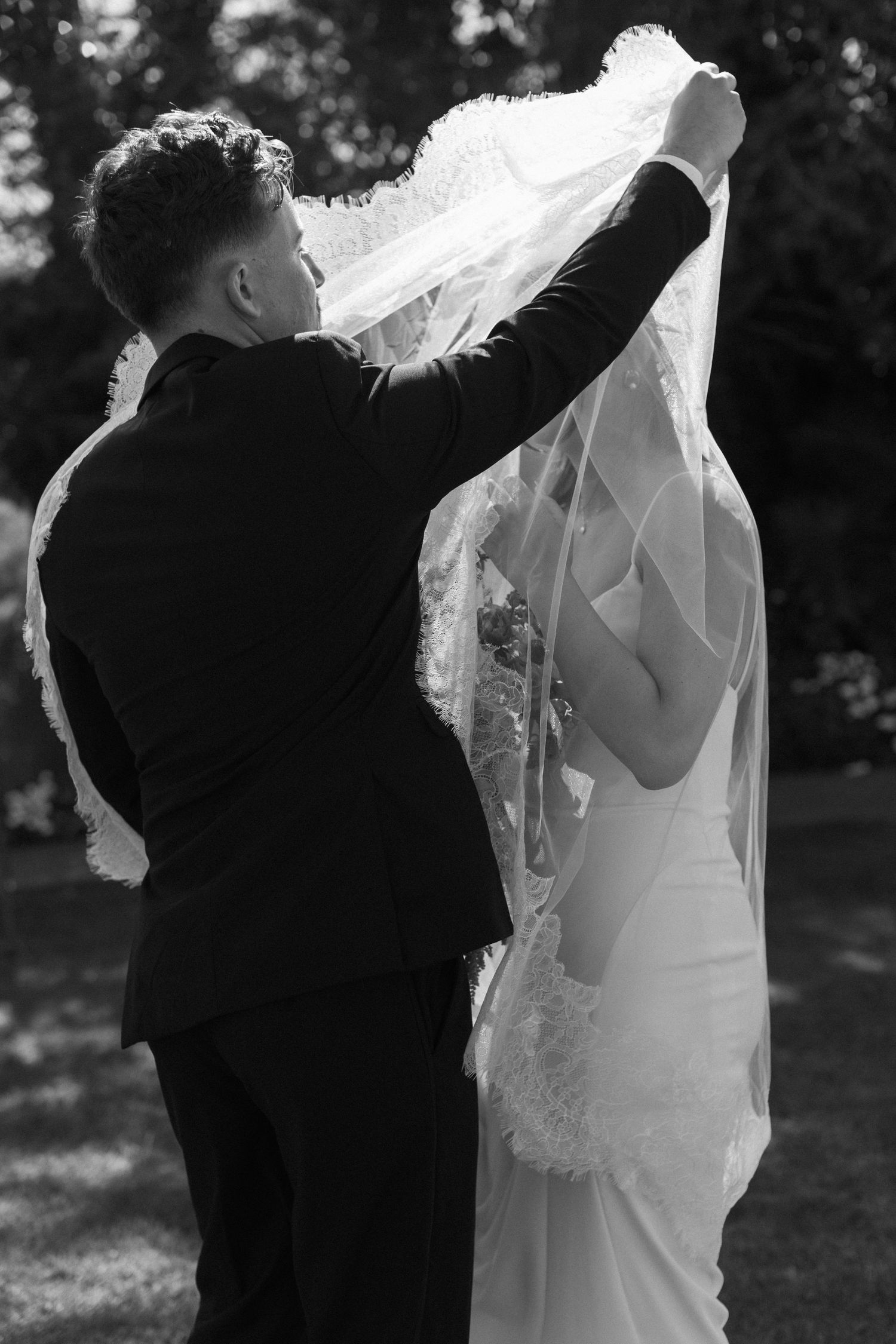 Black and white photos of a groom lifting his bride's delicate veil during an outdoor wedding ceremony.