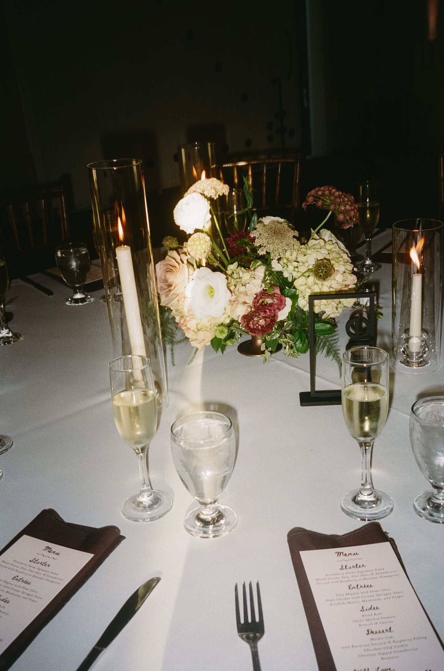 Wedding reception table with place settings, menus, and delicate floral centerpieces.