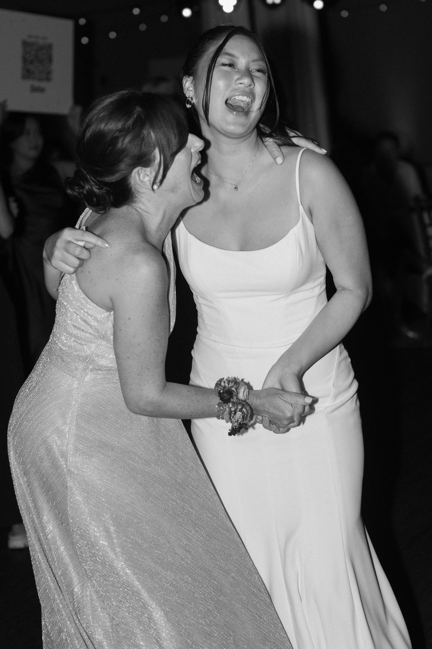 Wedding guests in white and sparkly dresses dance energetically at the reception.