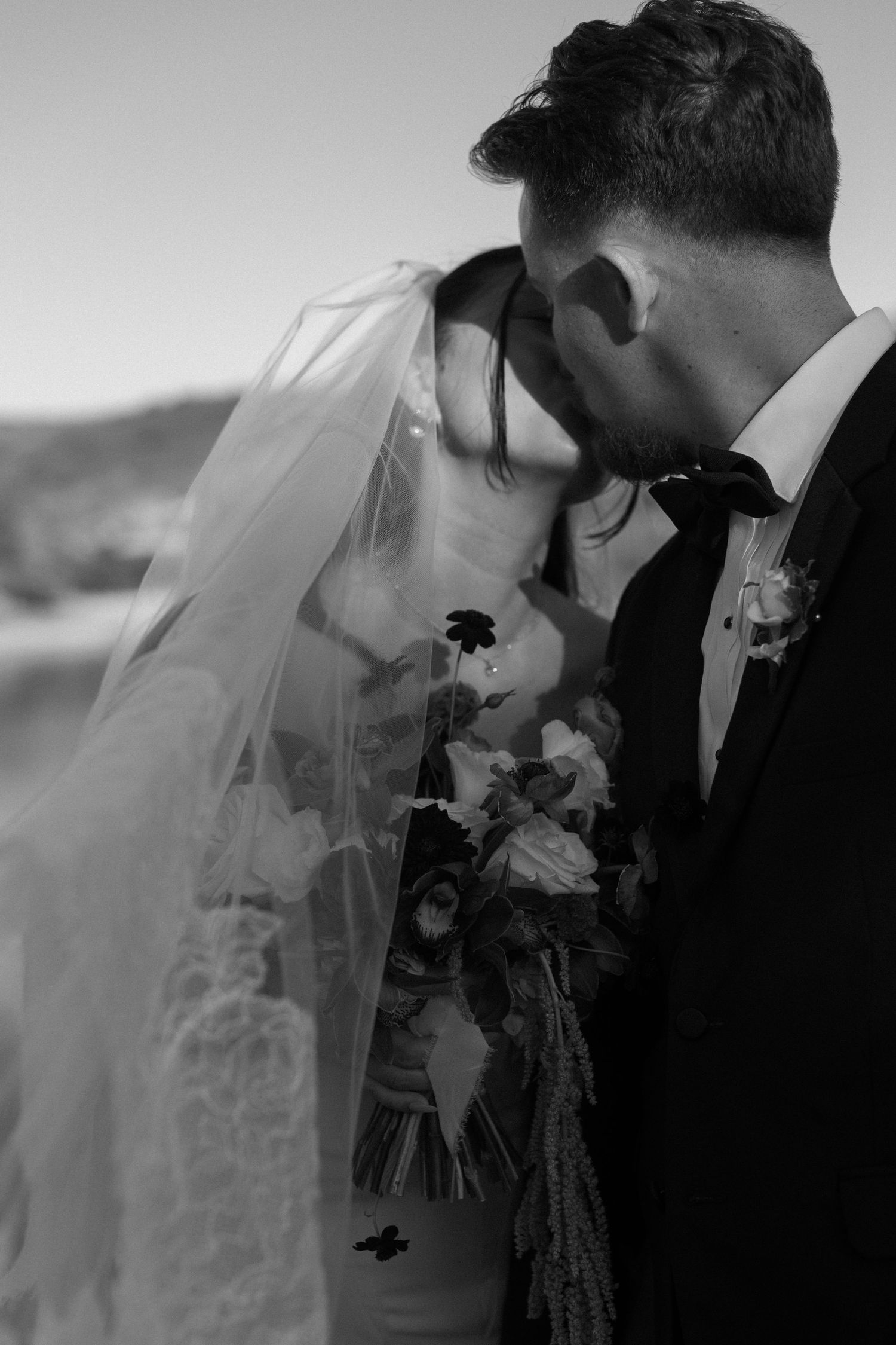 A romantic black and white wedding portrait sequence with a flowing veil and floral bouquet.