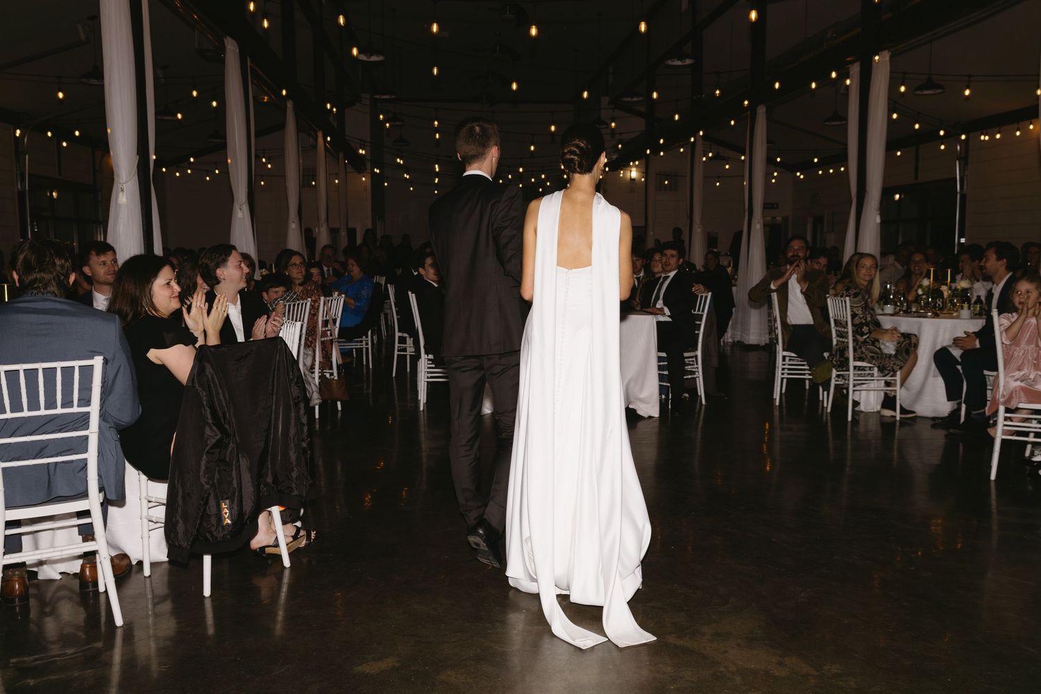 Wedding reception venue with string lights and guests seated at tables.