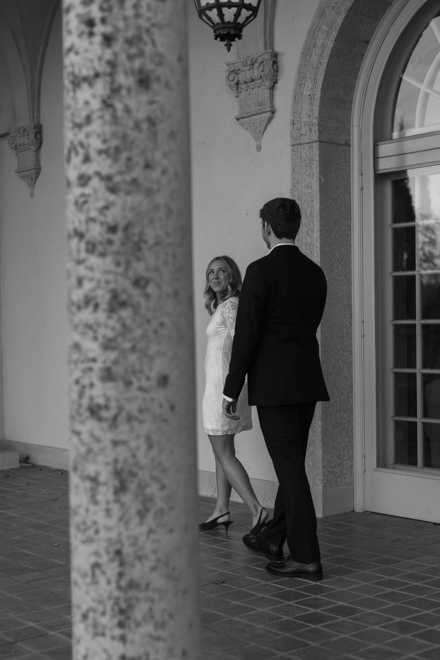 Black and white wedding photo series capturing romantic moments in an ornate architectural setting.