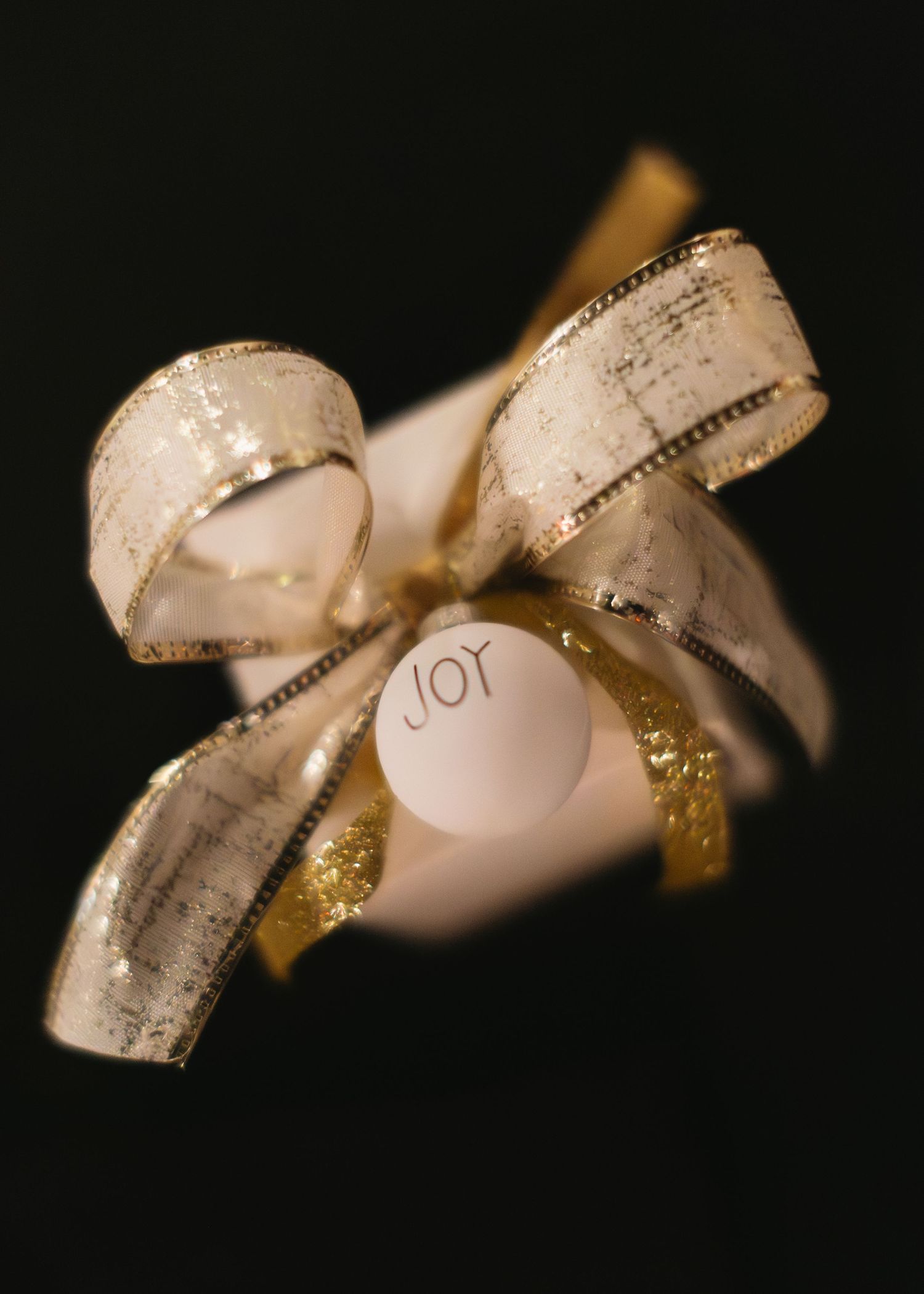 Decorative pink ribbon with gold trim and text against a dark background.
