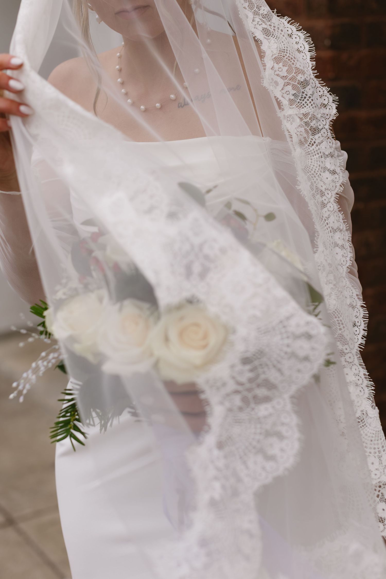 Close-up details of delicate white lace and roses on a wedding veil.