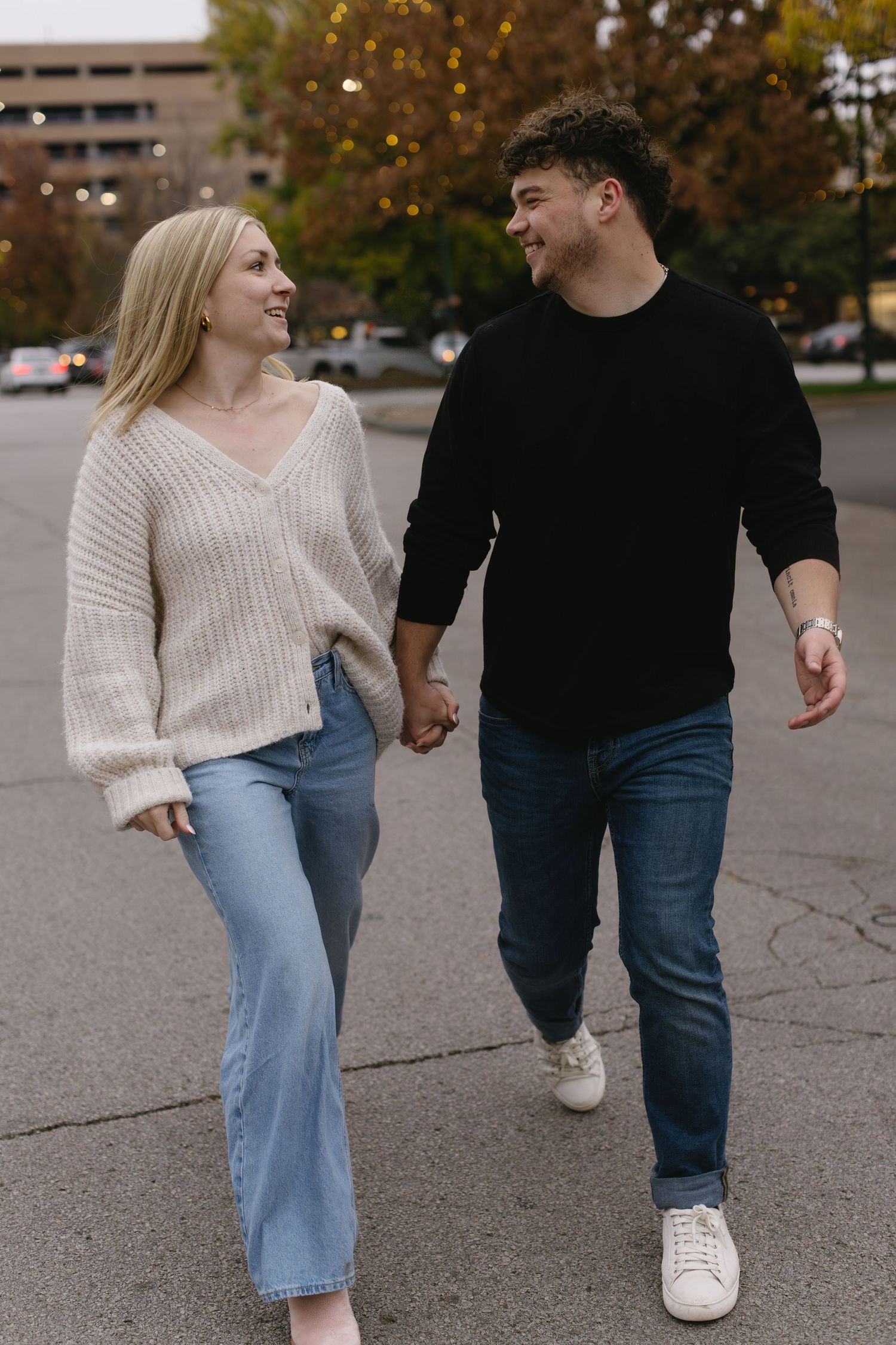 Couple walking hand in hand through a parking lot on an autumn day.