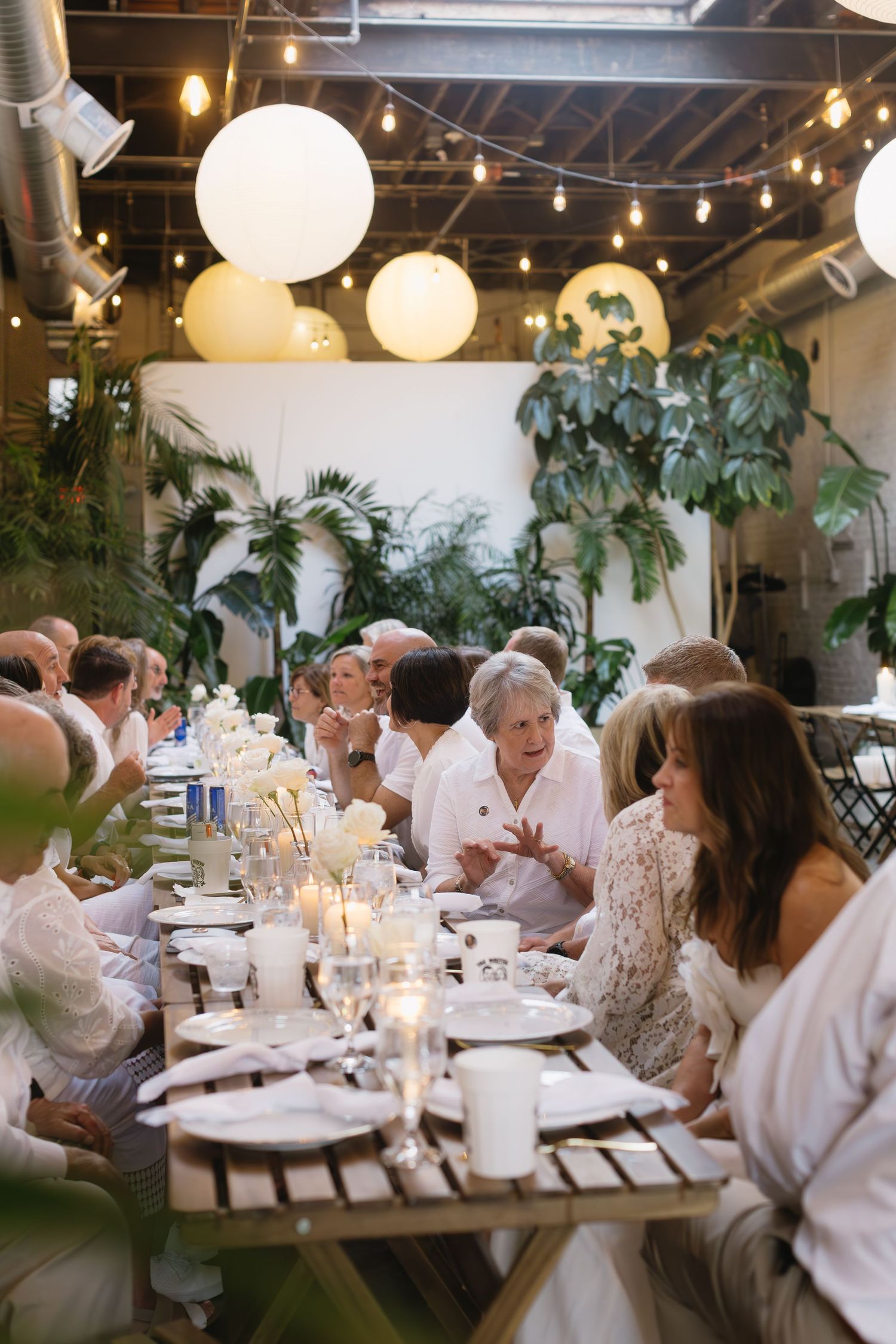 An indoor reception with string lights and white paper lanterns creating an intimate dining atmosphere.