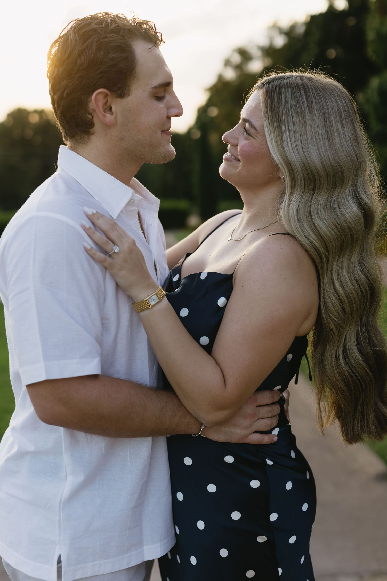 A couple shares an intimate dance moment while wearing polka dots and white in an outdoor setting.