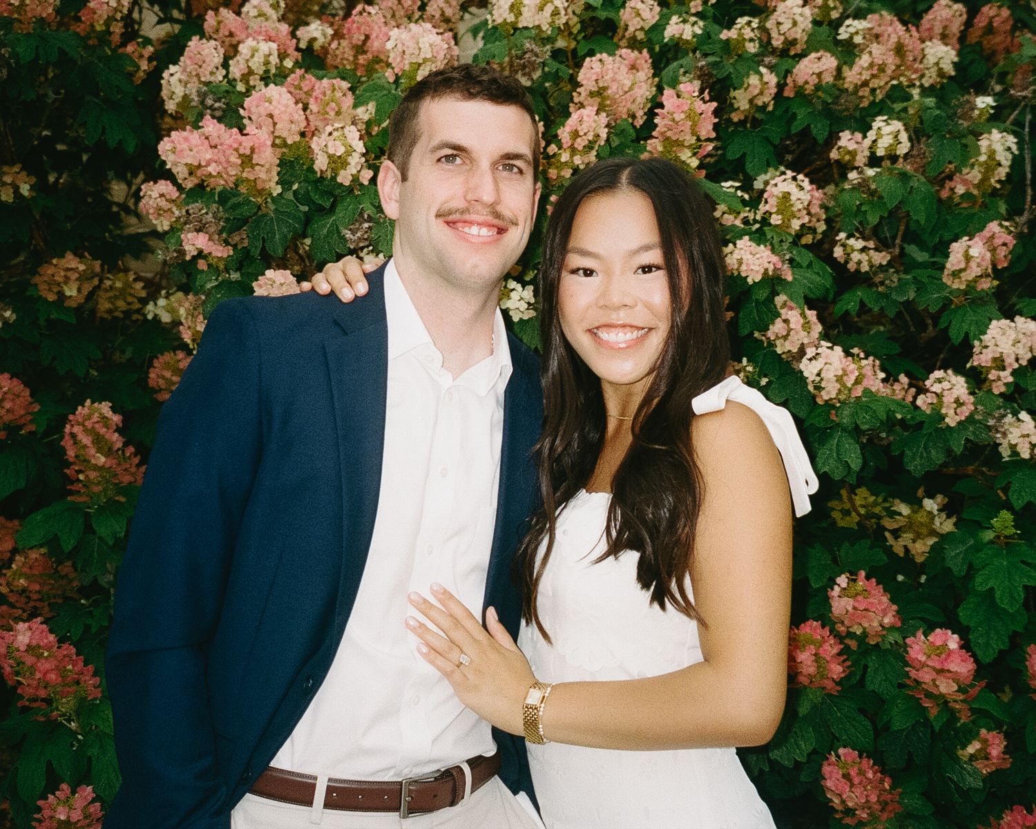 Romantic photo session with flowering pink bushes creating a beautiful natural backdrop.