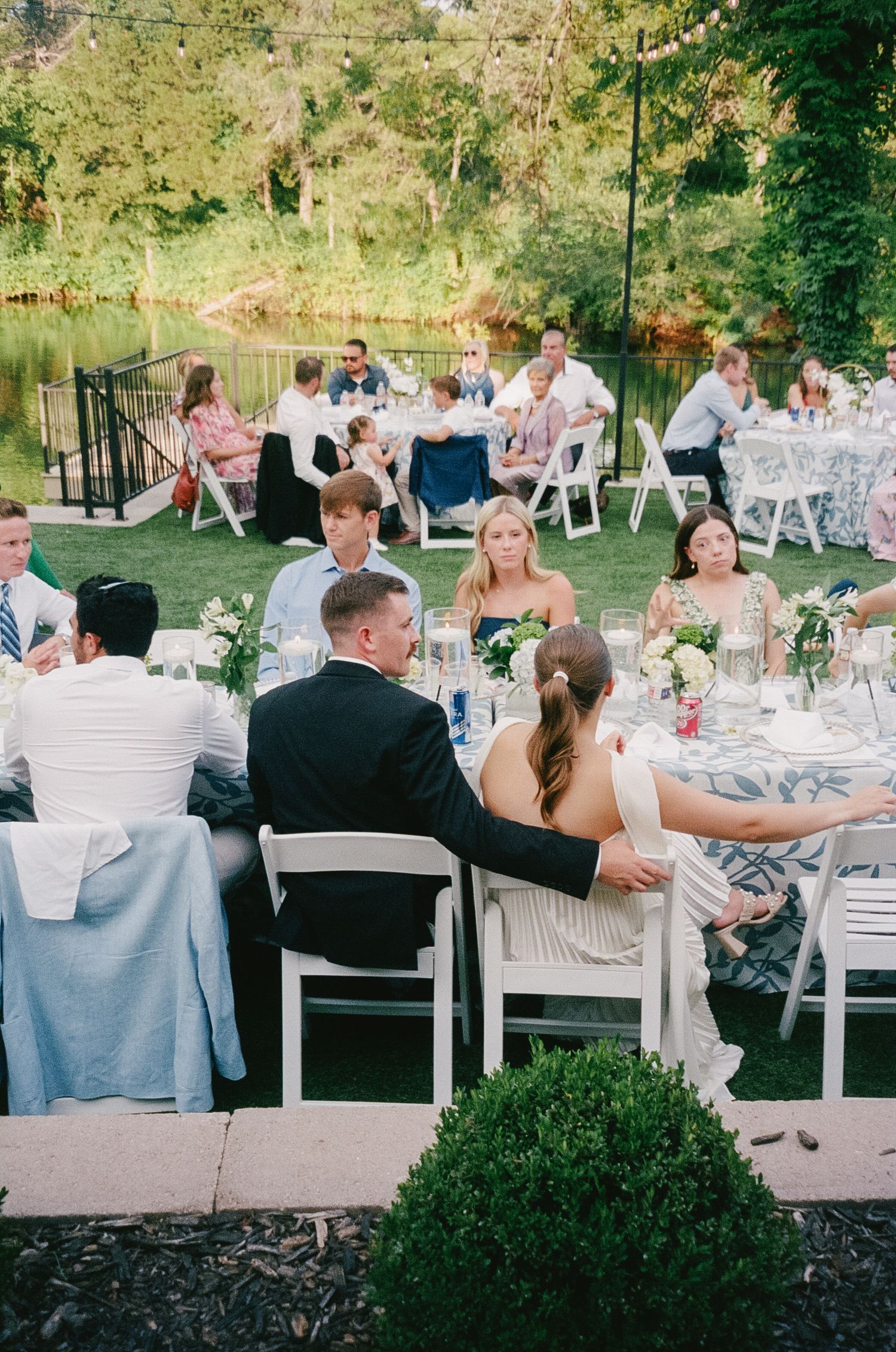 Outdoor wedding reception tables decorated with floral centerpieces and white tablecloths for guests to dine al fresco.