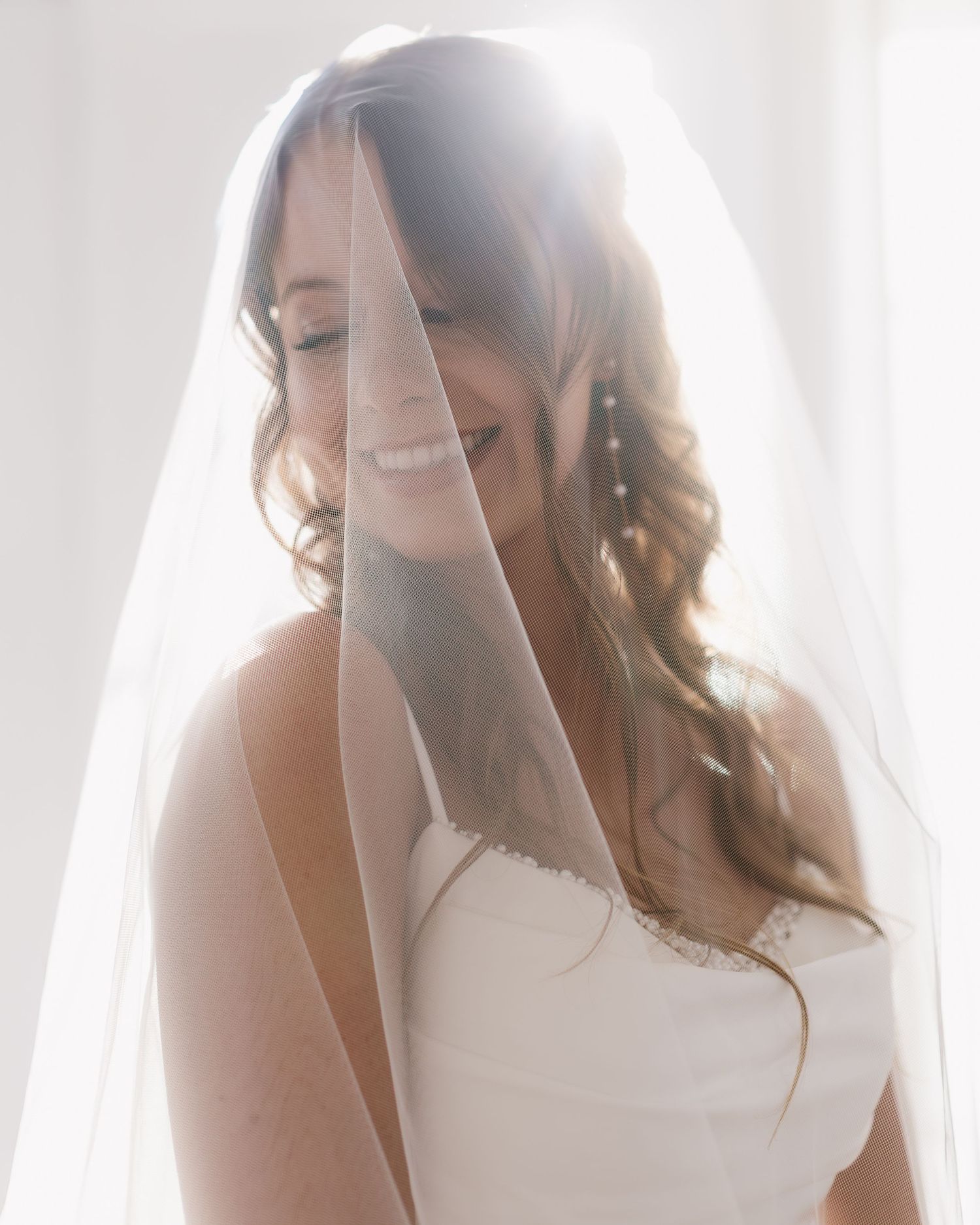 Soft-focus close-up of a bride wearing a delicate veil in natural window light.