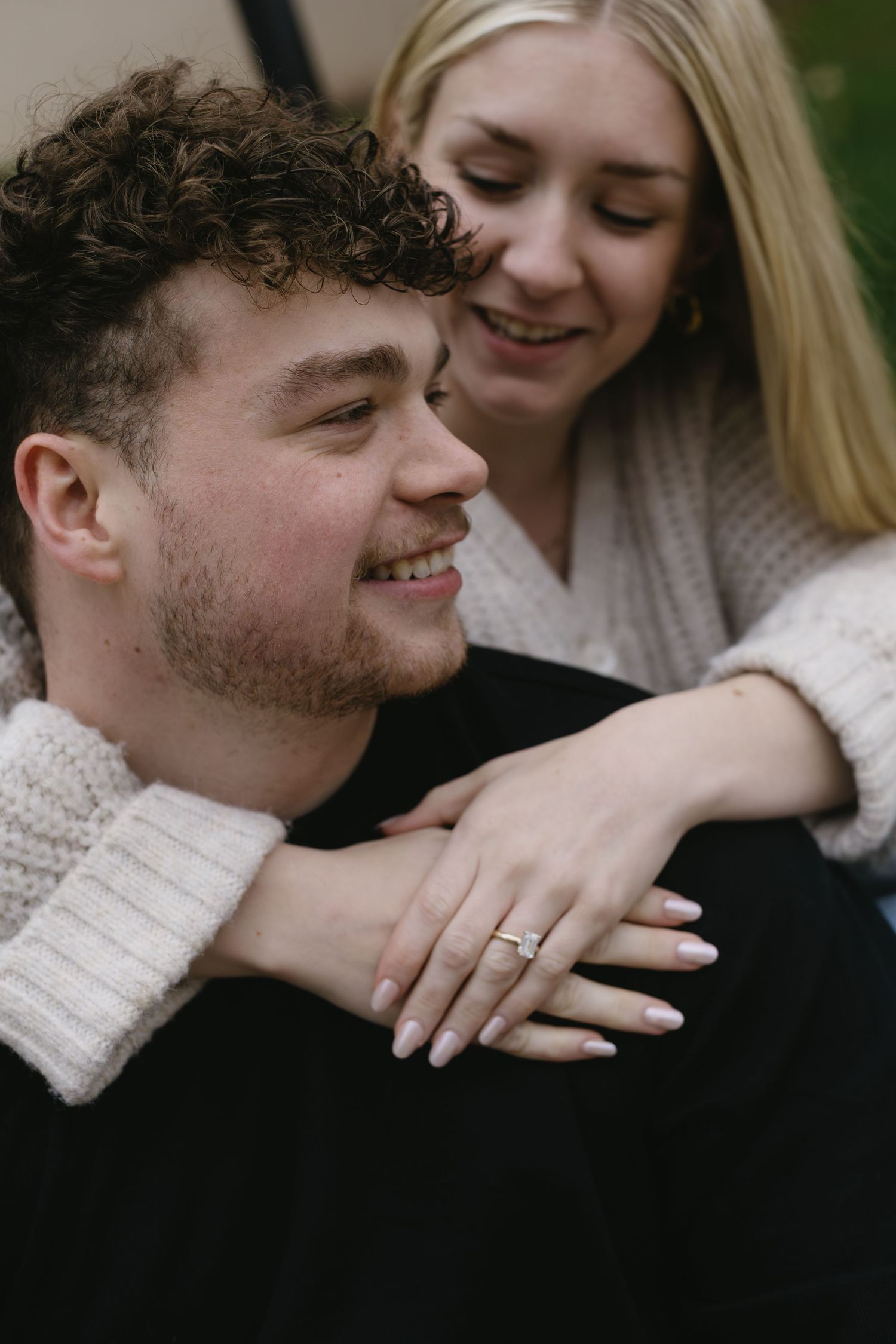 An intimate engagement photo showing off a ring while the couple shares a close embrace.